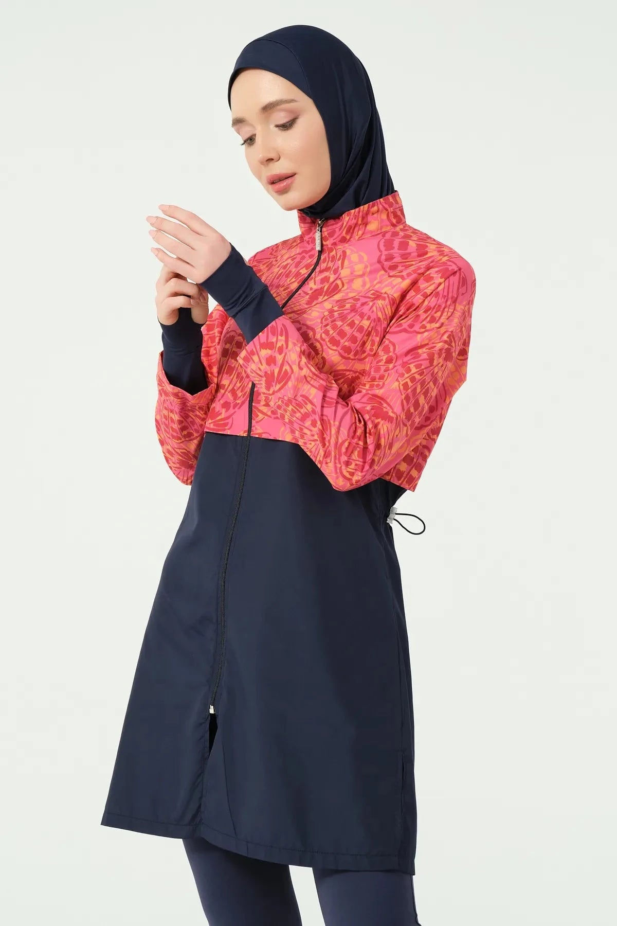 Woman in navy and coral burkini looking down at hands.