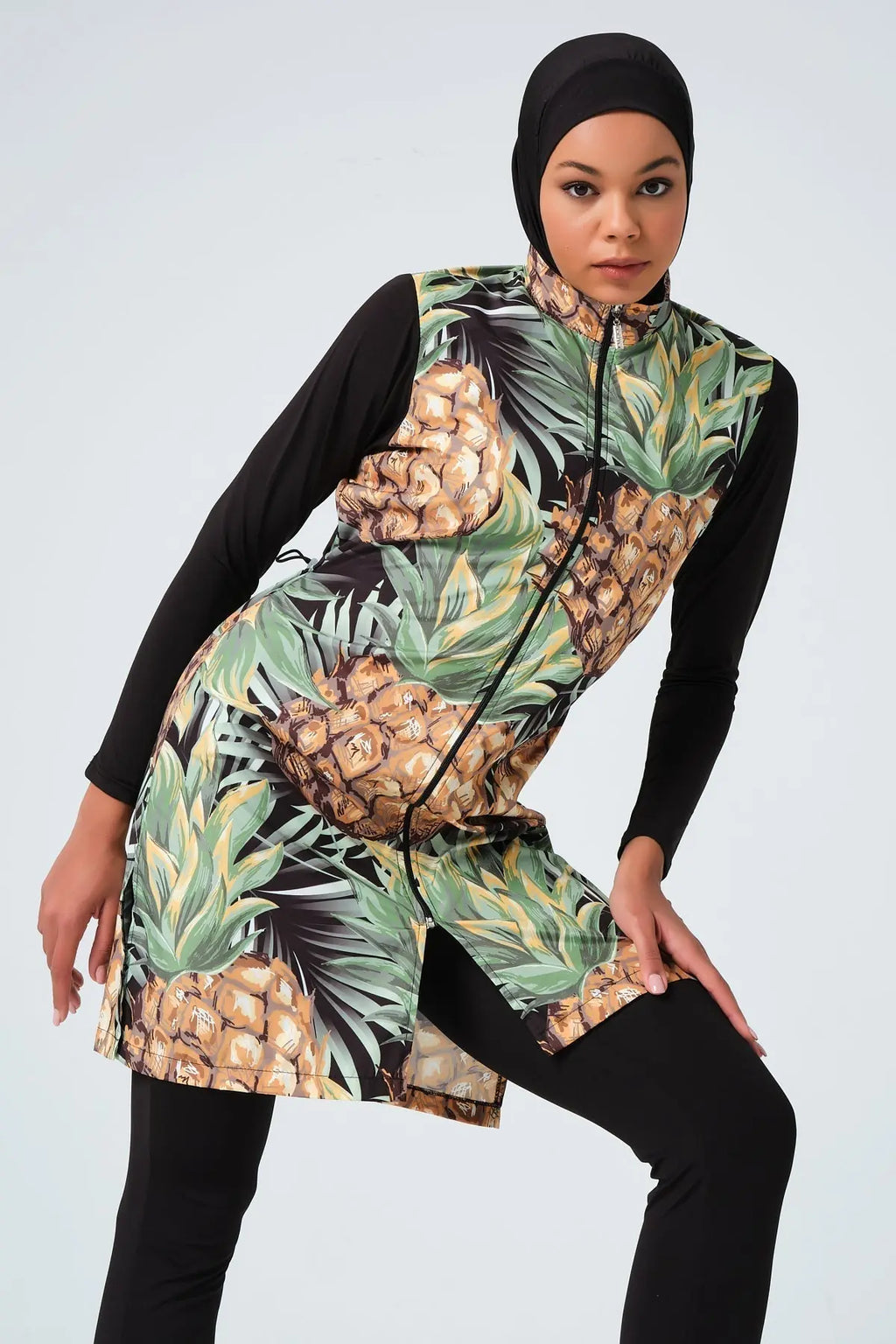 Model in pineapple print burkini with zip-up front, angled pose.