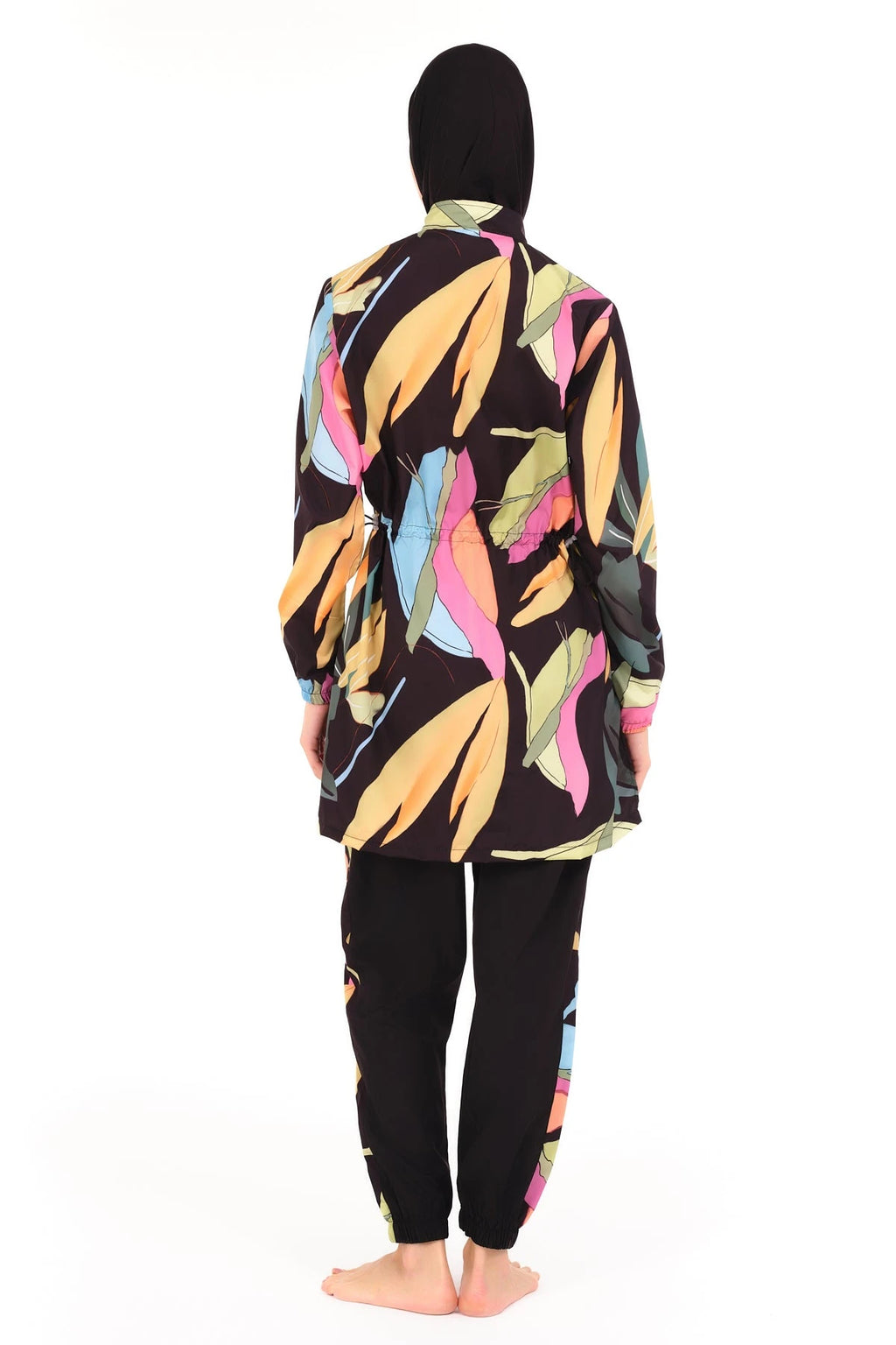 Back view of woman in black tropical print burkini with jogger pants.