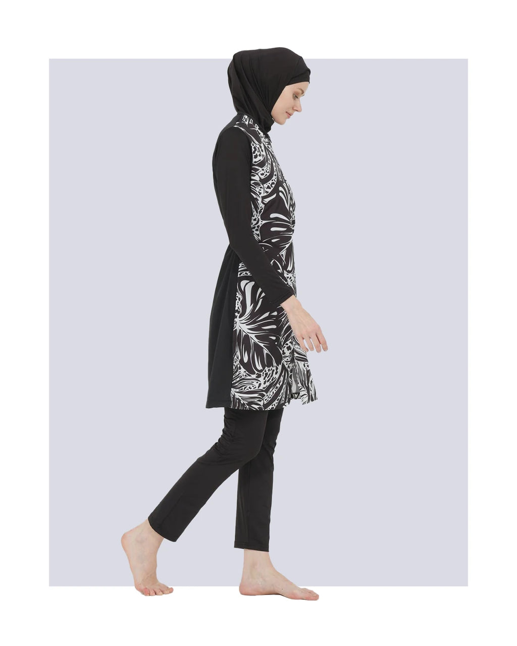 Model in black and white burkini set, side view walking.