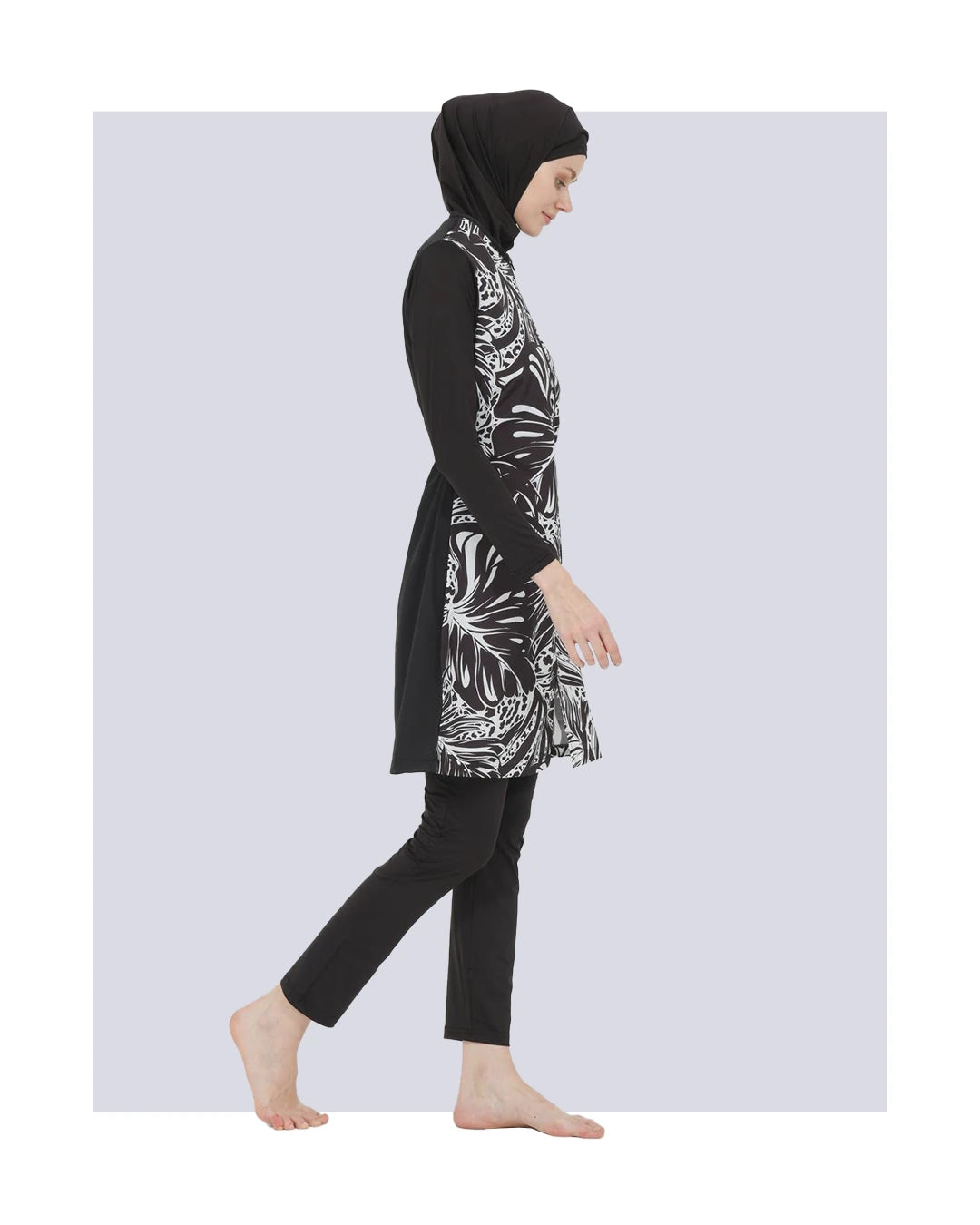 Model in black and white burkini set, side view walking.