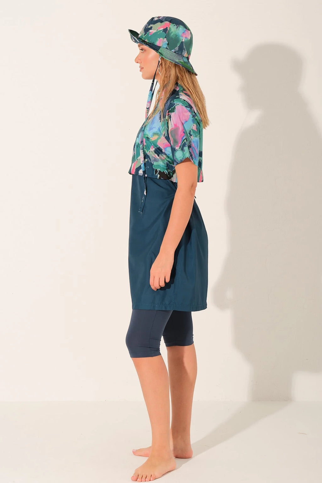 Side view of woman in water-repellent burkini set and floral bucket hat.