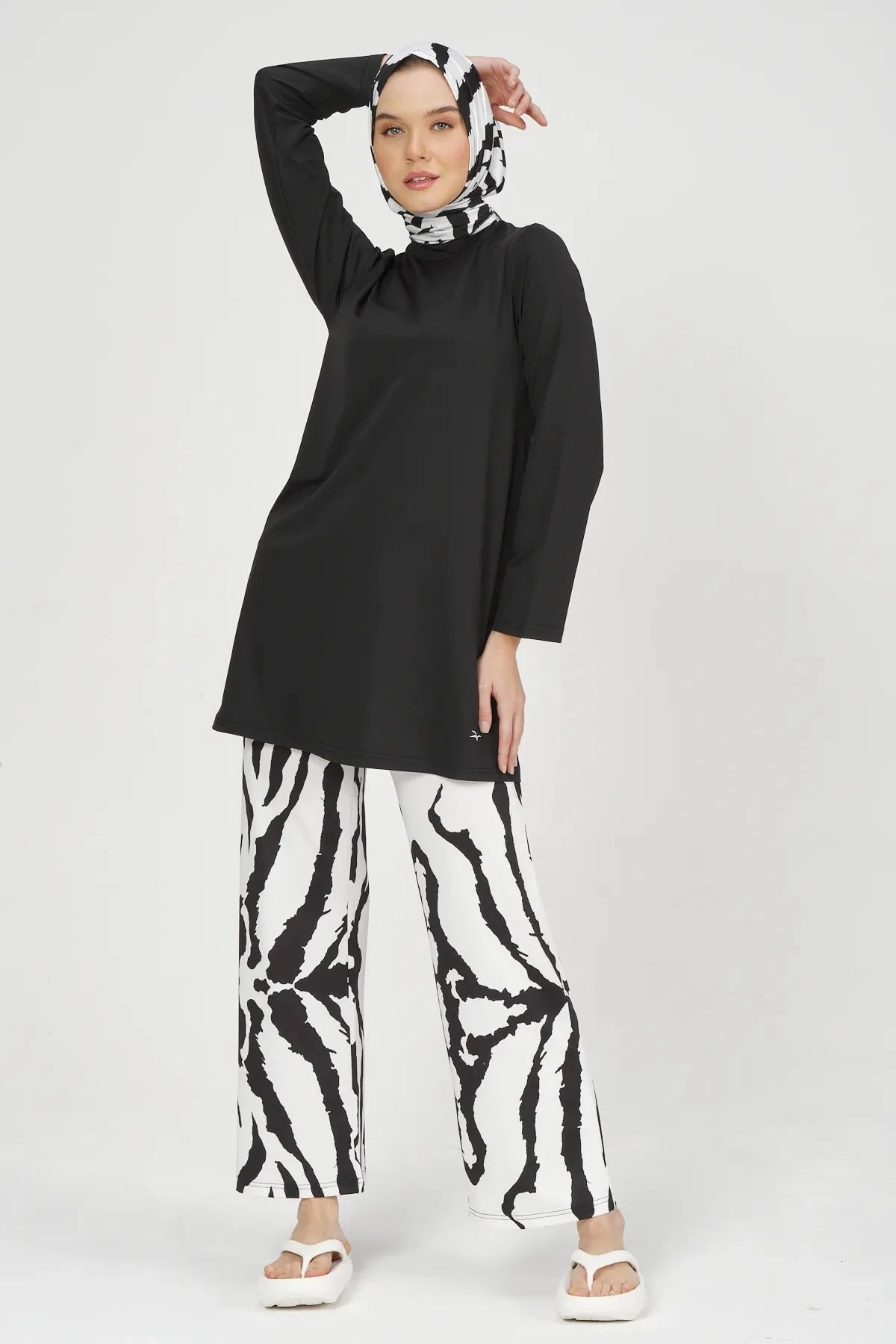 Woman posing in black tunic, zebra print burkini pants, and matching hijab.