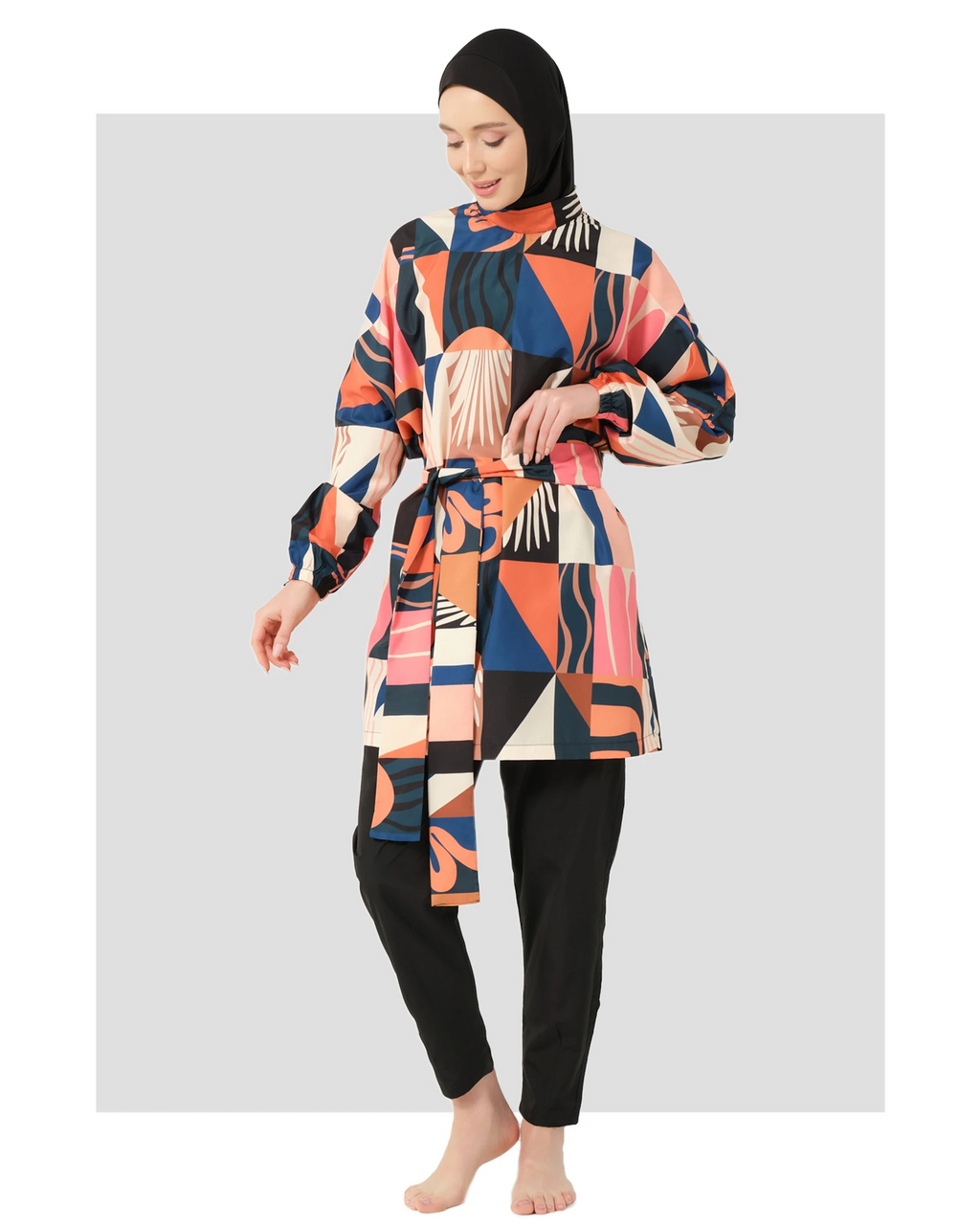 Woman in multi-color geometric print modest swimsuit with belt, front view.