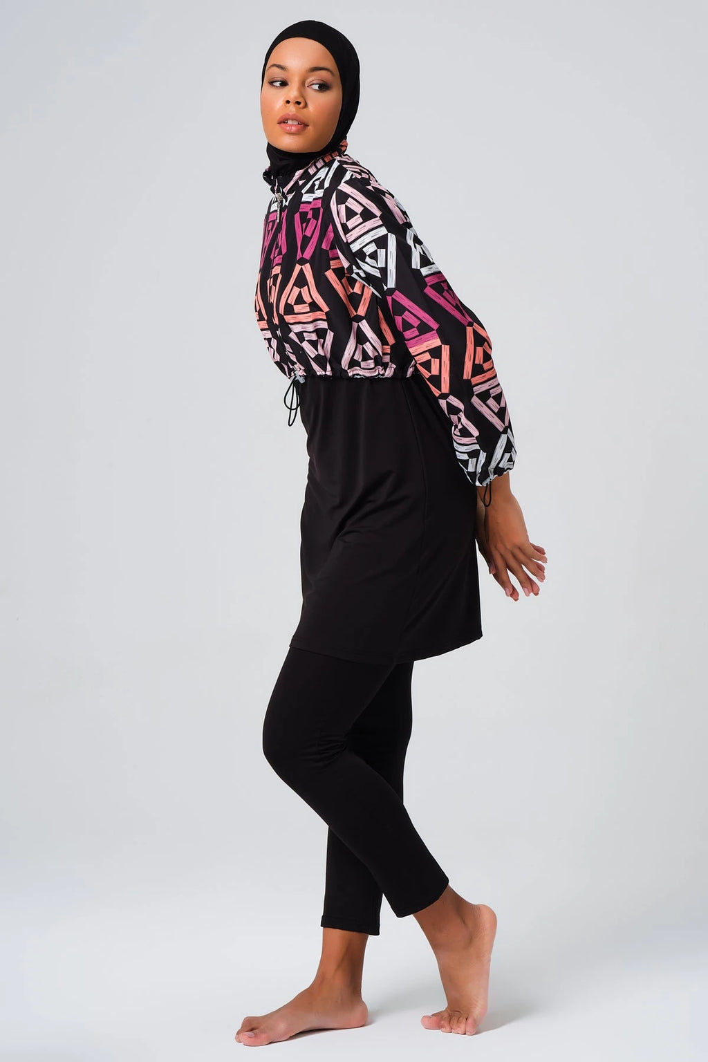 Modest swimsuit set with geometric print jacket, side profile, black hijab.