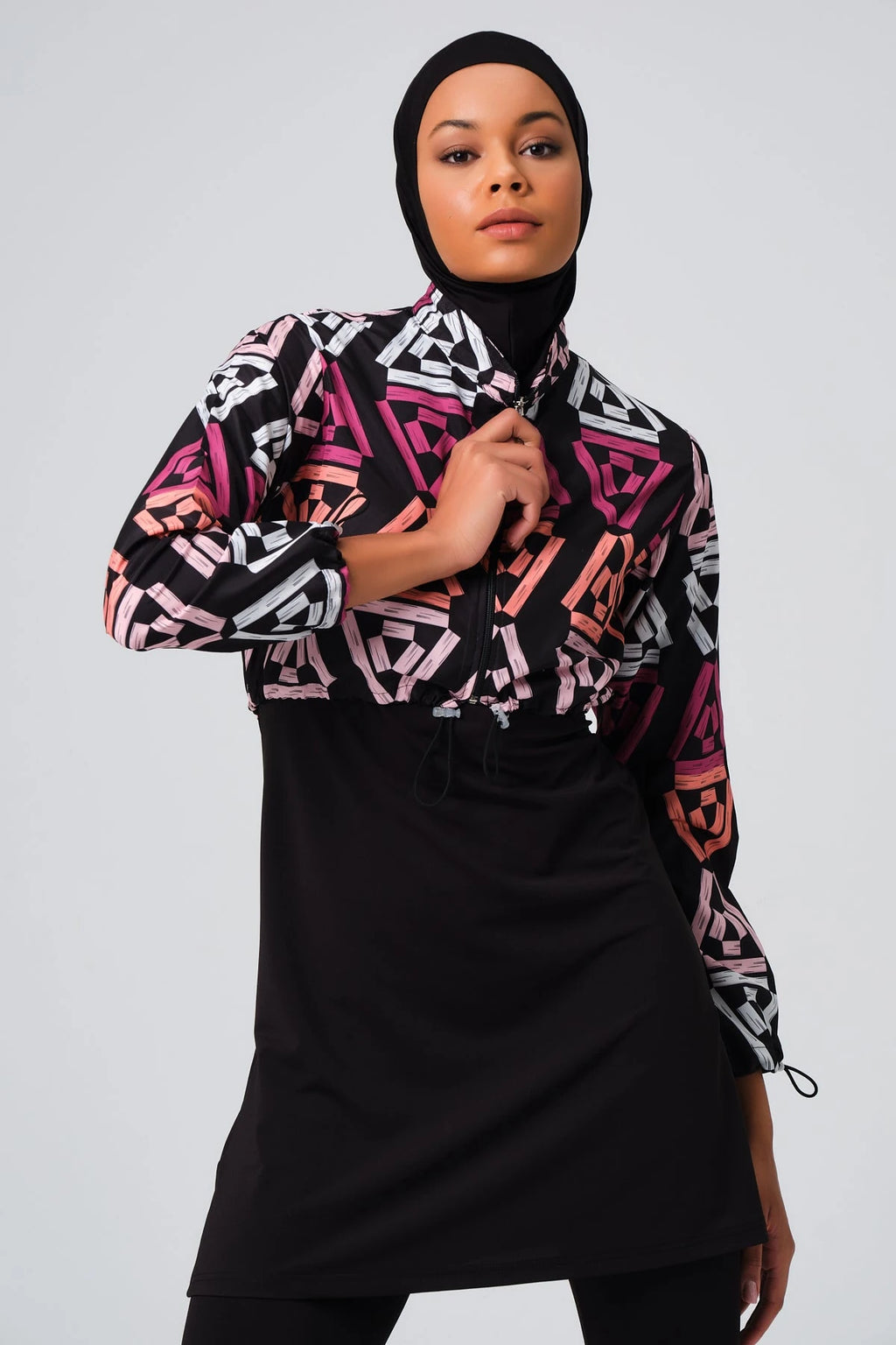 Woman in geometric print modest swimsuit jacket, adjusting collar.