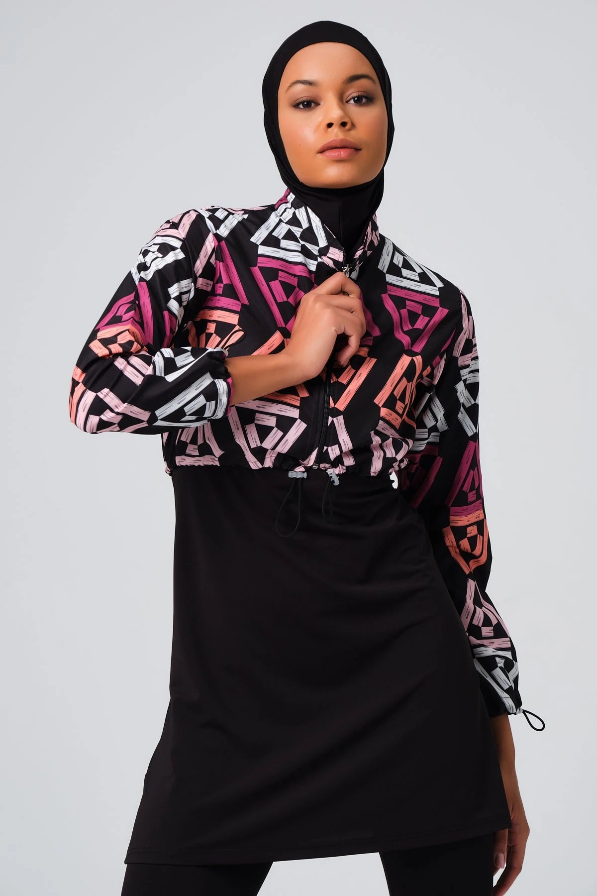 Woman in geometric print modest swimsuit jacket, adjusting collar.