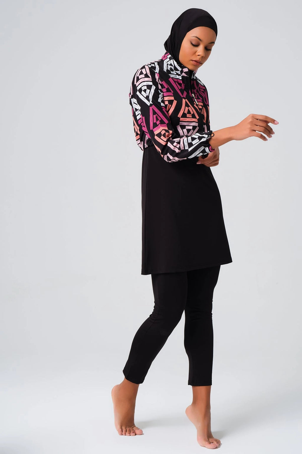 Woman wearing geometric print modest swimsuit set, full body view.