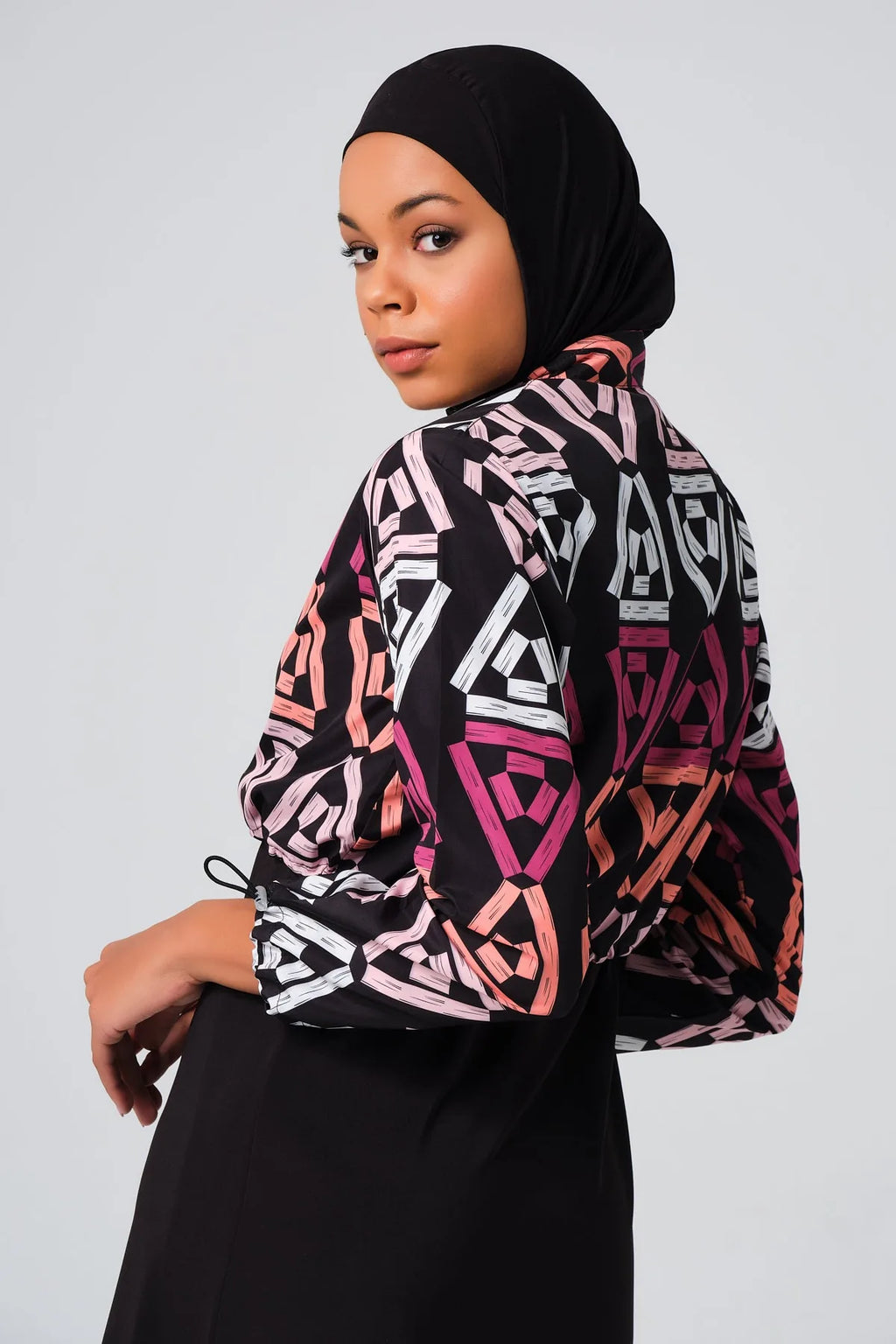 Close-up of woman in geometric print modest swimsuit, looking over shoulder.