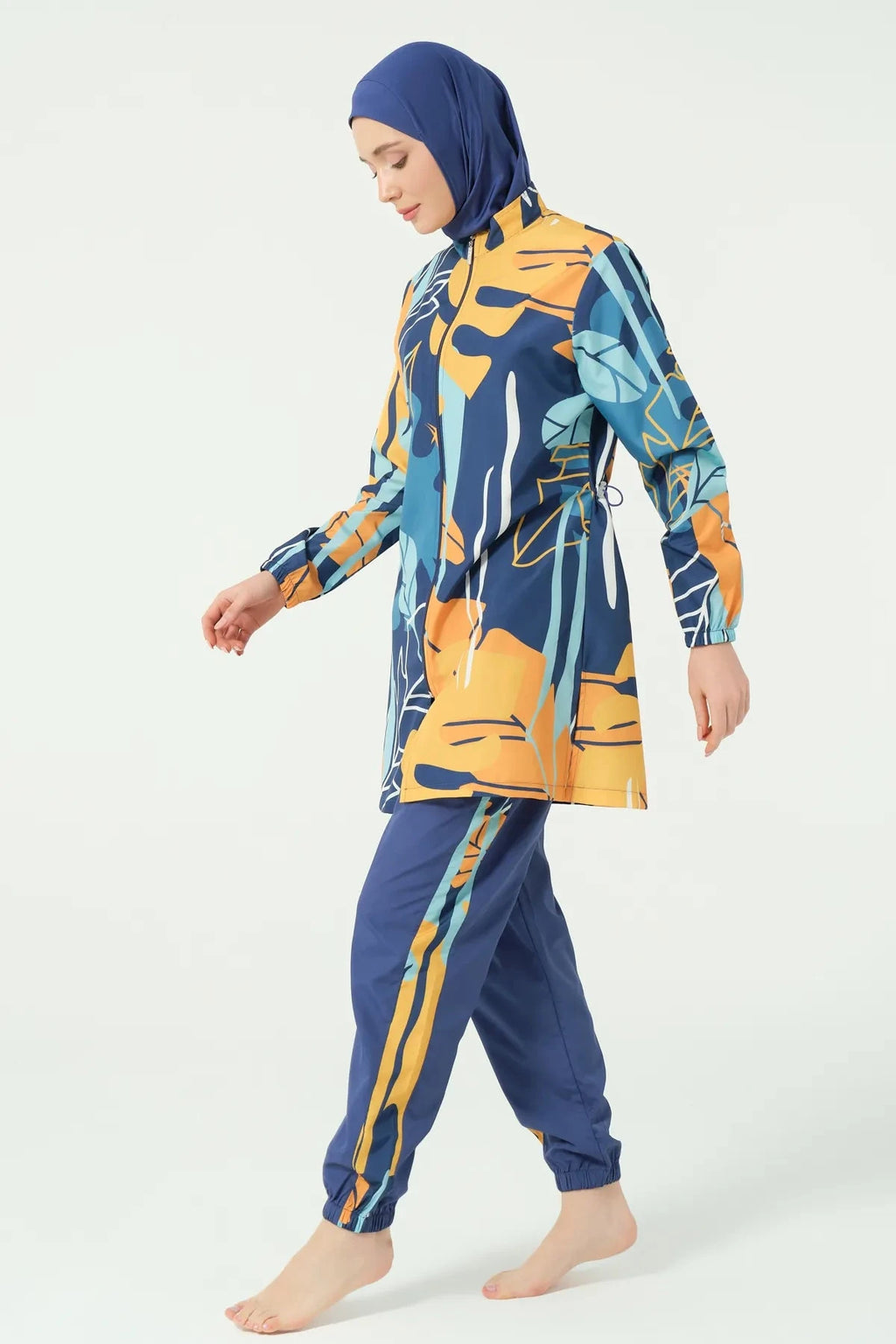 Woman walking in abstract print modest swimsuit side profile.