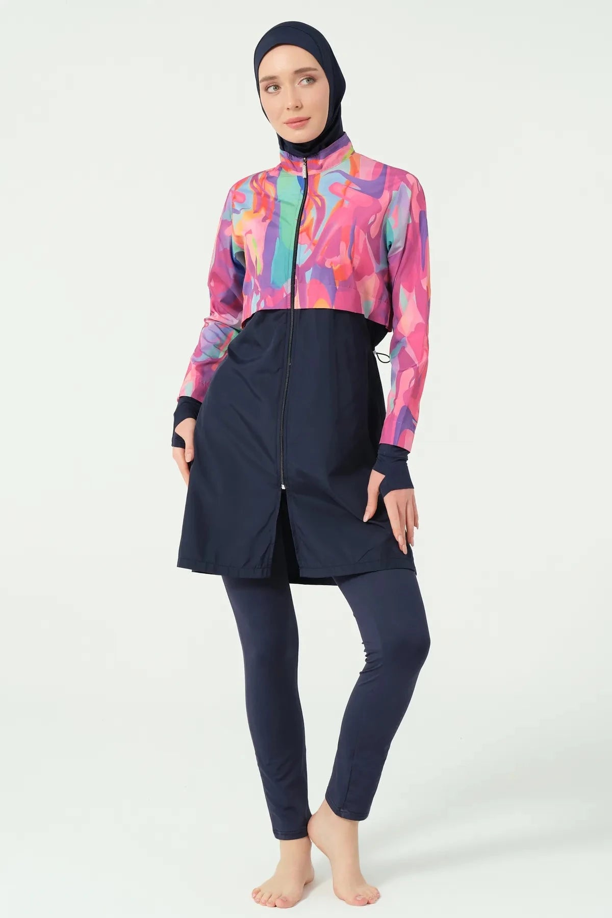 Model in abstract print burkini, front view, hands on hips, with zipper detail.