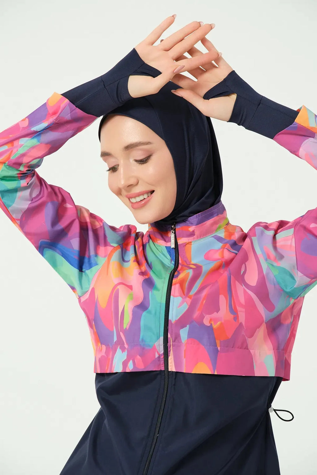 Close-up of model's head and hands in abstract print burkini, smiling.