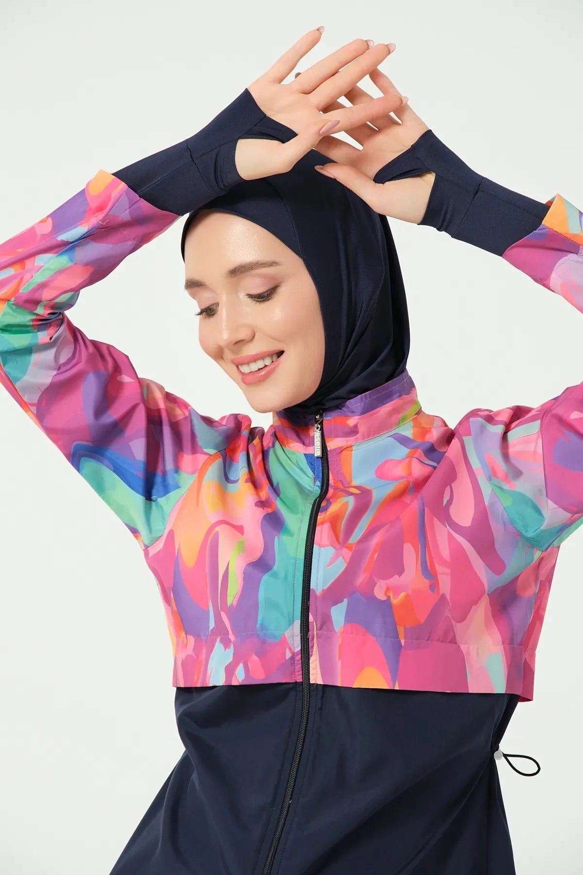 Close-up of model's head and hands in abstract print burkini, smiling.