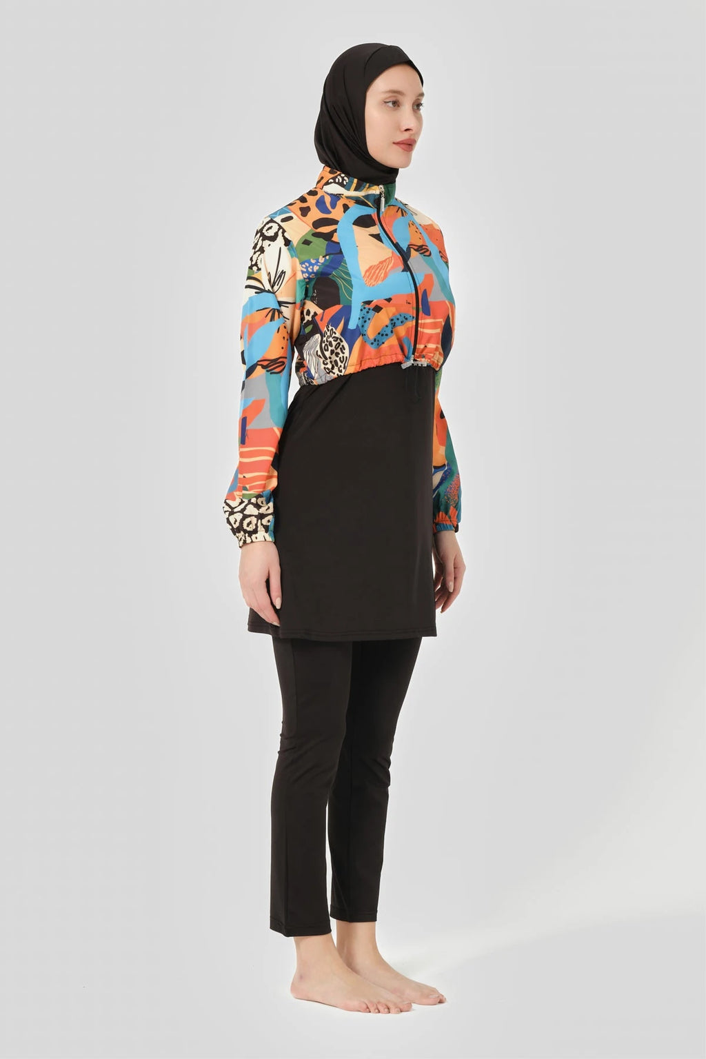Woman in vibrant abstract print hijab swimwear set, side profile.