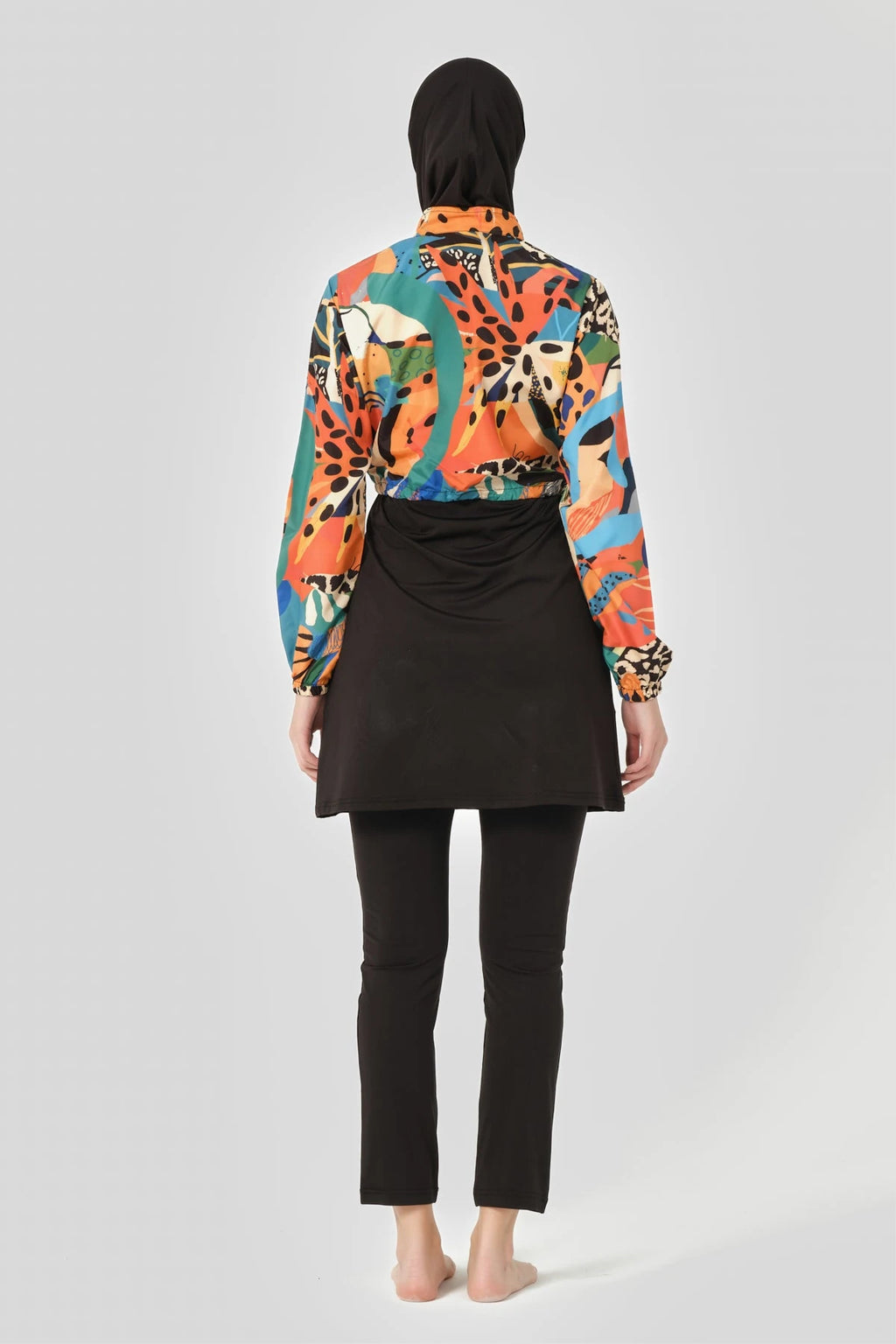 Woman in vibrant abstract print hijab swimwear set, back view.