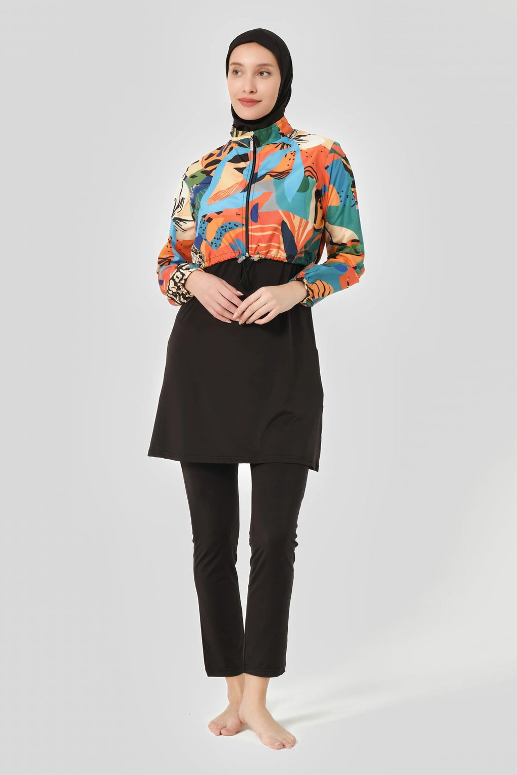 Woman in vibrant abstract print hijab swimwear set, front pose.