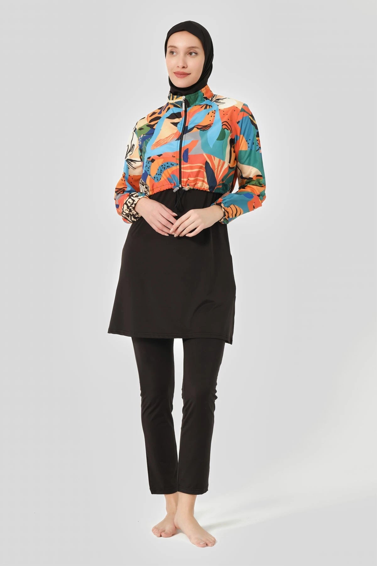 Woman in vibrant abstract print hijab swimwear set, front pose.