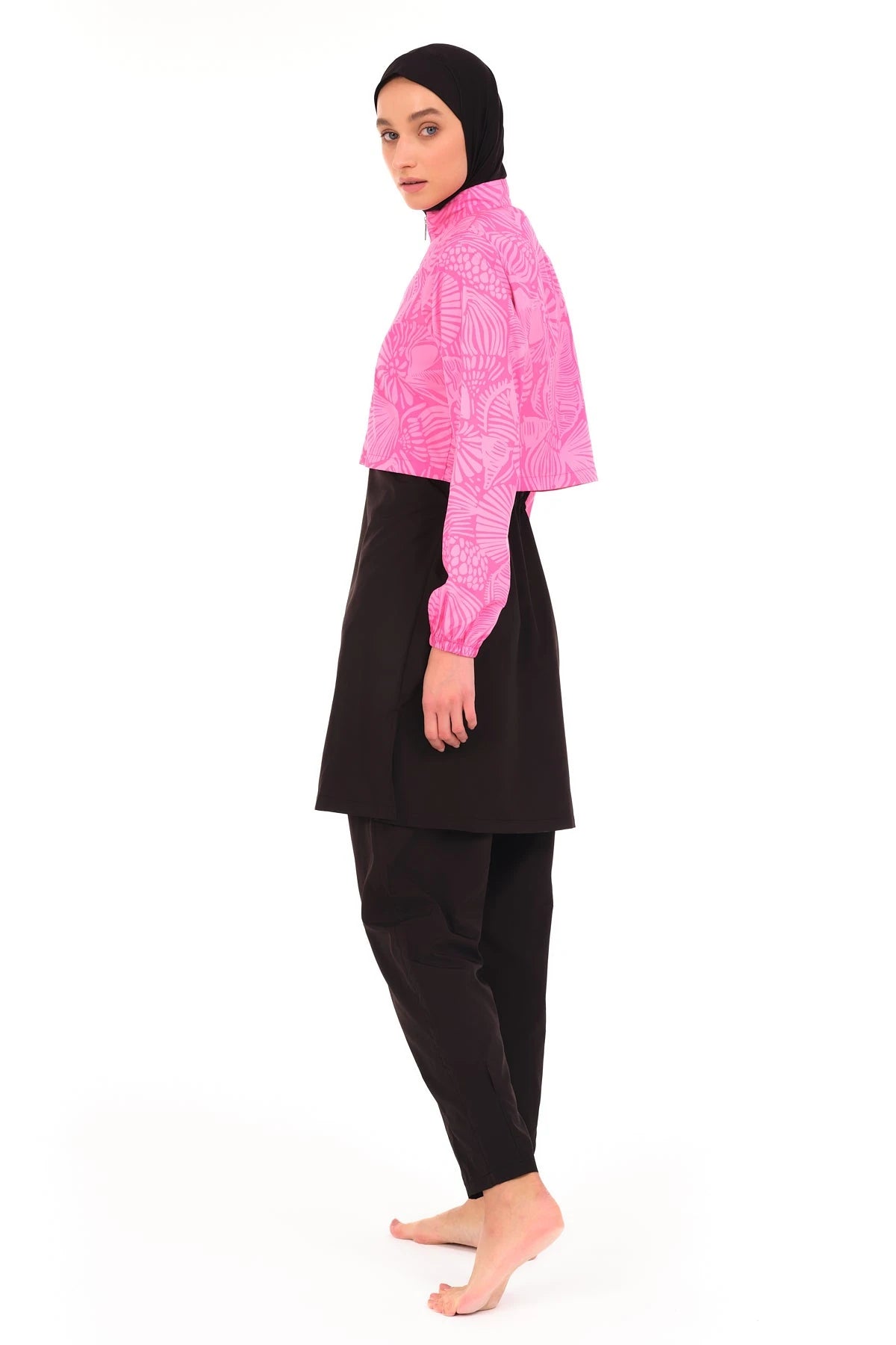 Side view of model in pink patterned cropped jacket and black full-coverage swimwear.
