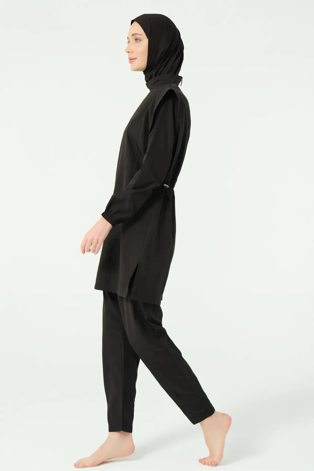 Black modest swimsuit side profile showing relaxed fit pants and long sleeves.