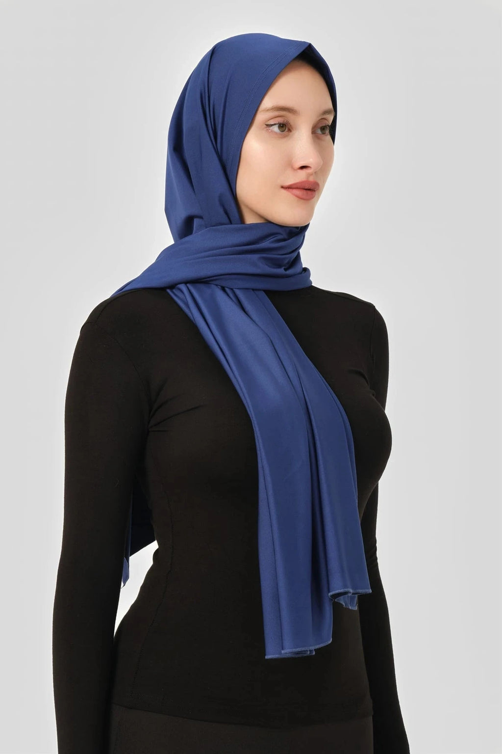 Blue swim hijab worn with black long-sleeved top, side profile view.