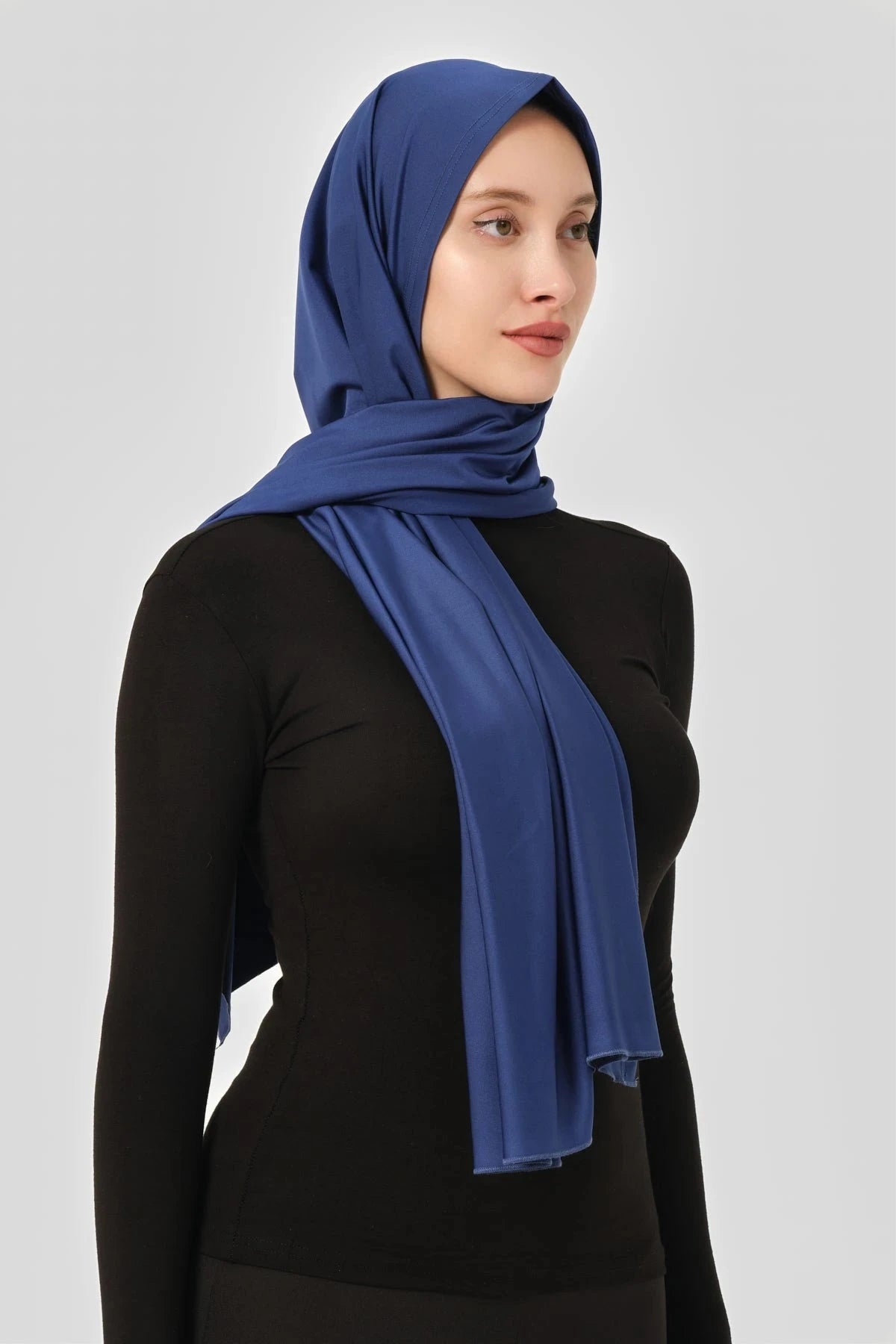 Blue swim hijab worn with black long-sleeved top, side profile view.