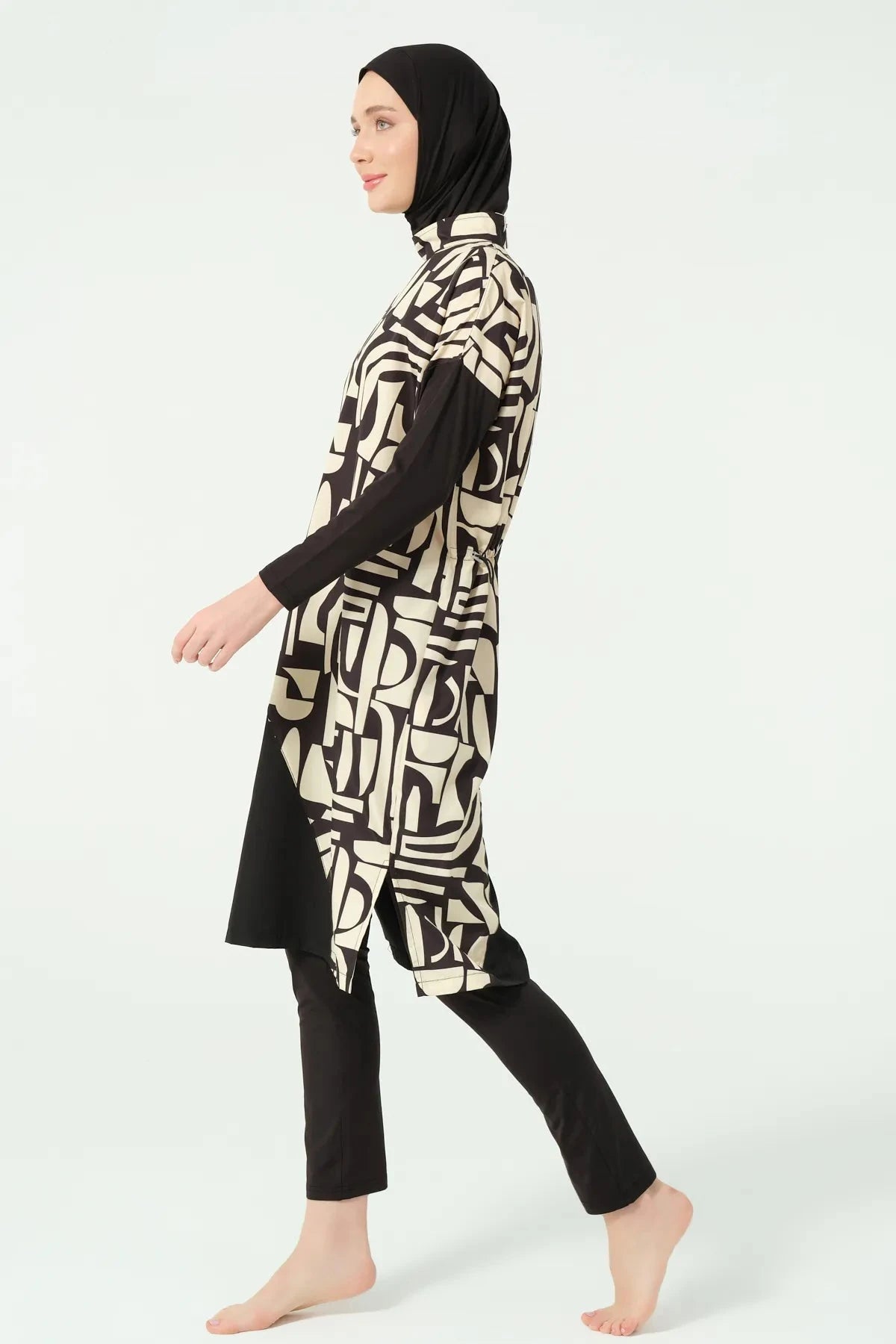 Model walking in black and beige geometric print burkini side view.