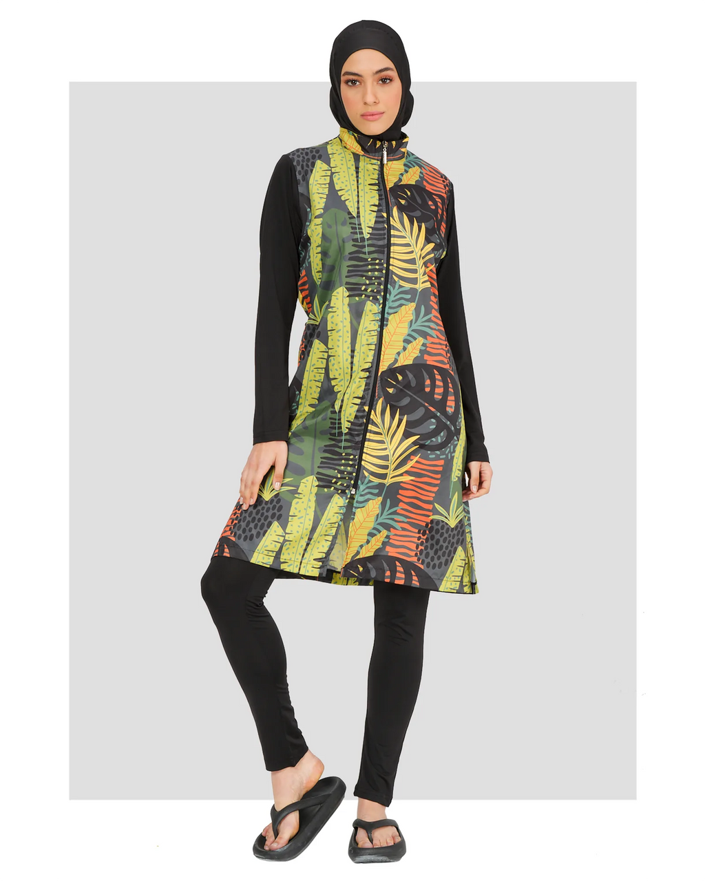Woman in green tropical print burkini with black leggings and hijab, front view.