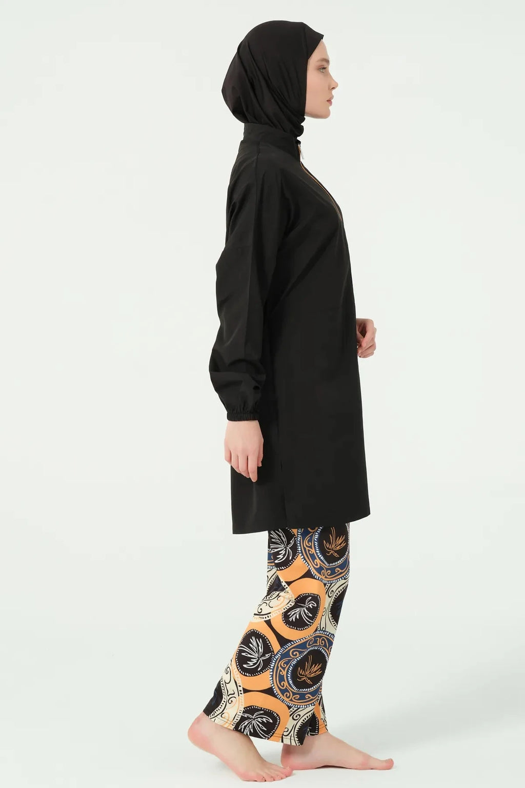 Side view of model in black tunic and printed swim pants.