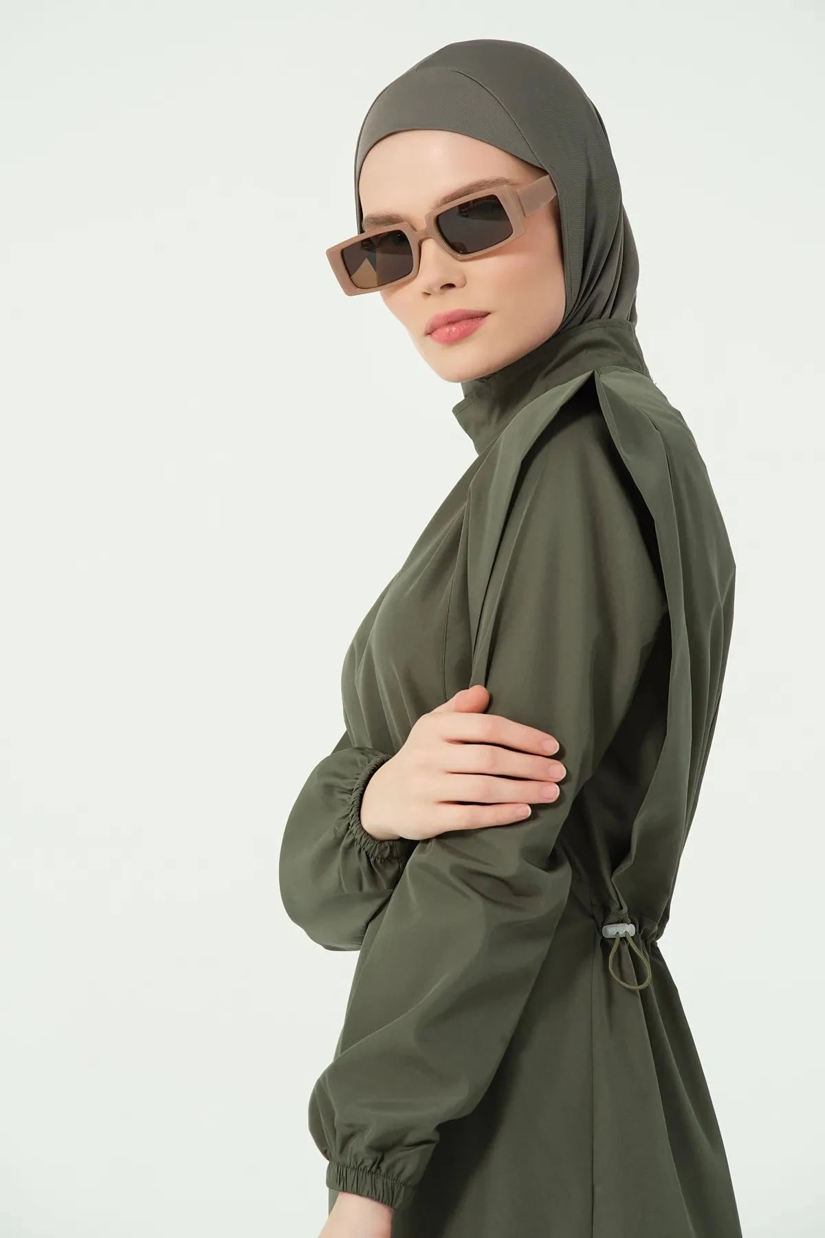 Close-up side profile of khaki modest swimsuit and sunglasses.