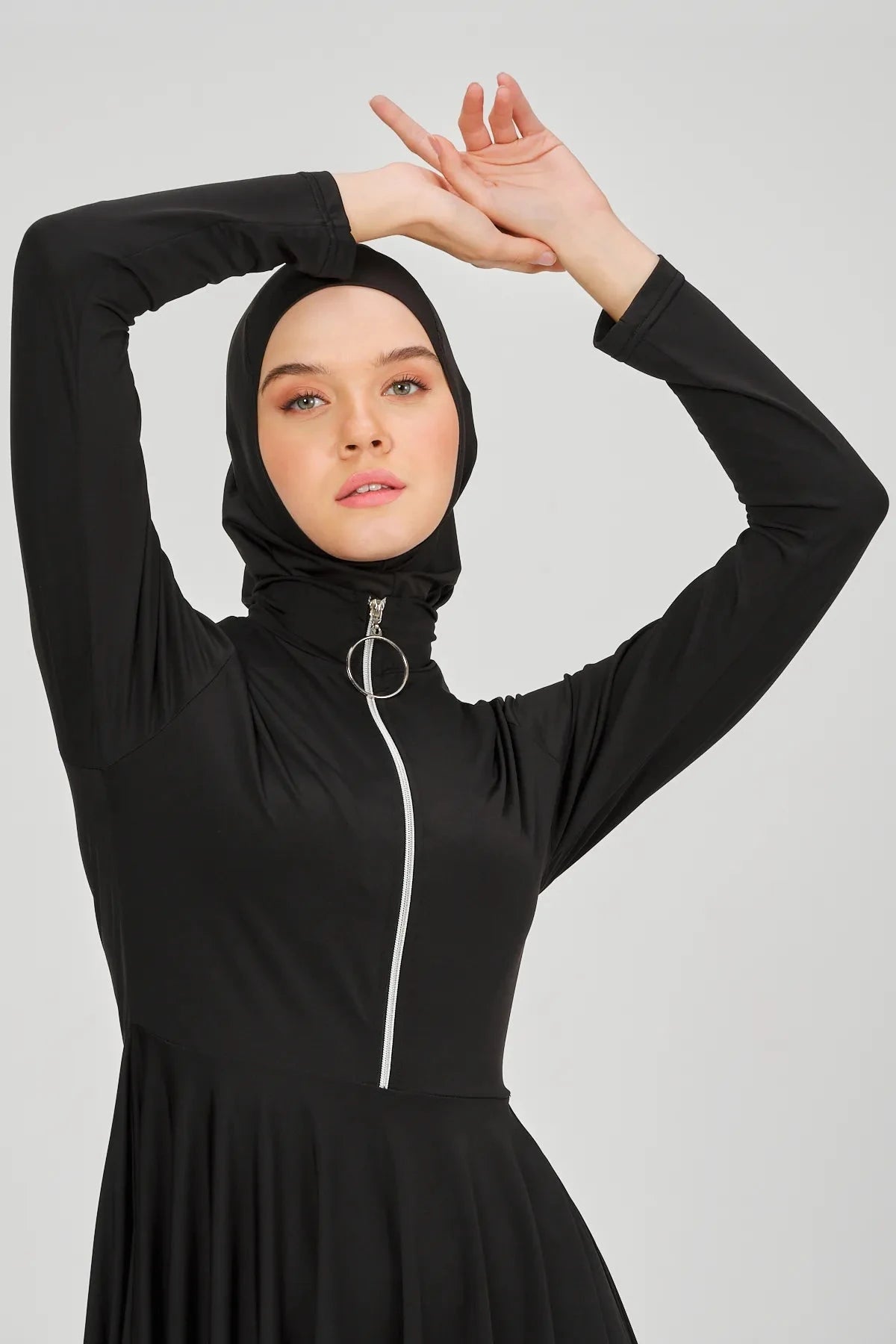 Close-up of model's face, black flared modest swimsuit top and hijab