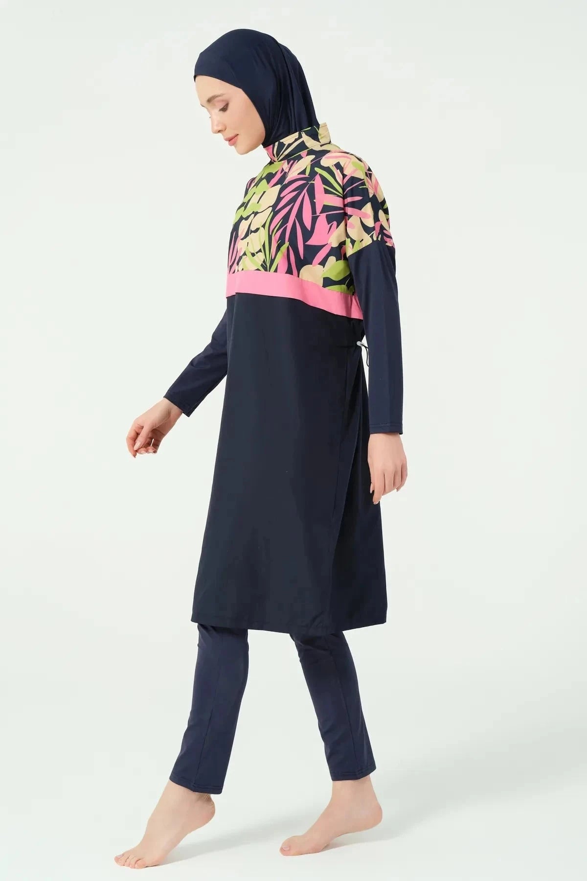 Side view of woman in navy tropical print burkini walking.