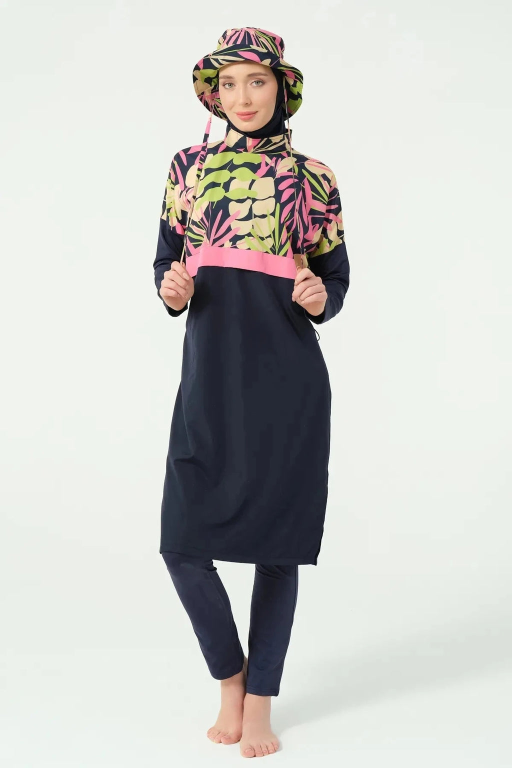Front view of woman in navy tropical print burkini with bucket hat.