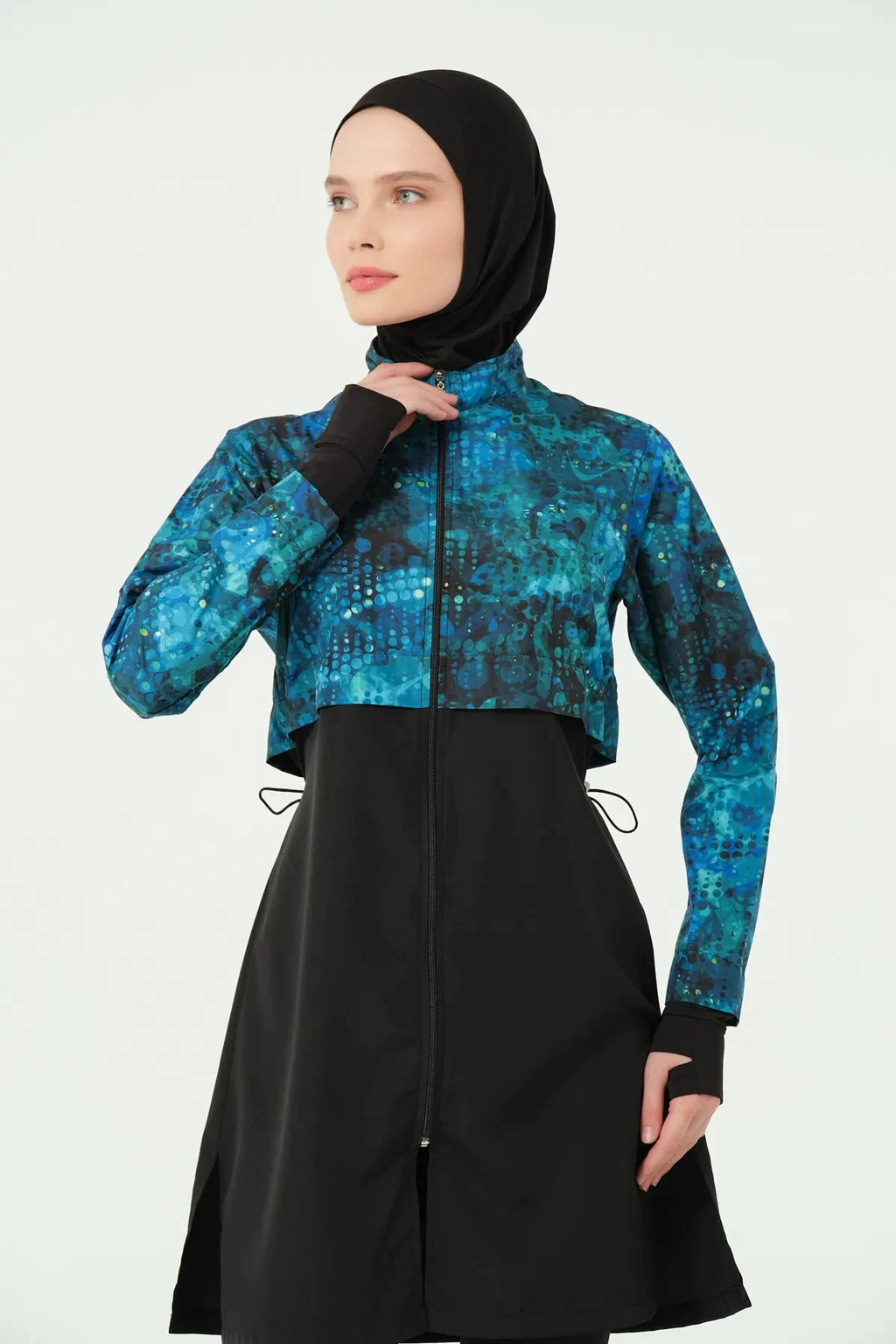 Upper section of teal and black hijab swimwear, model touching neck.