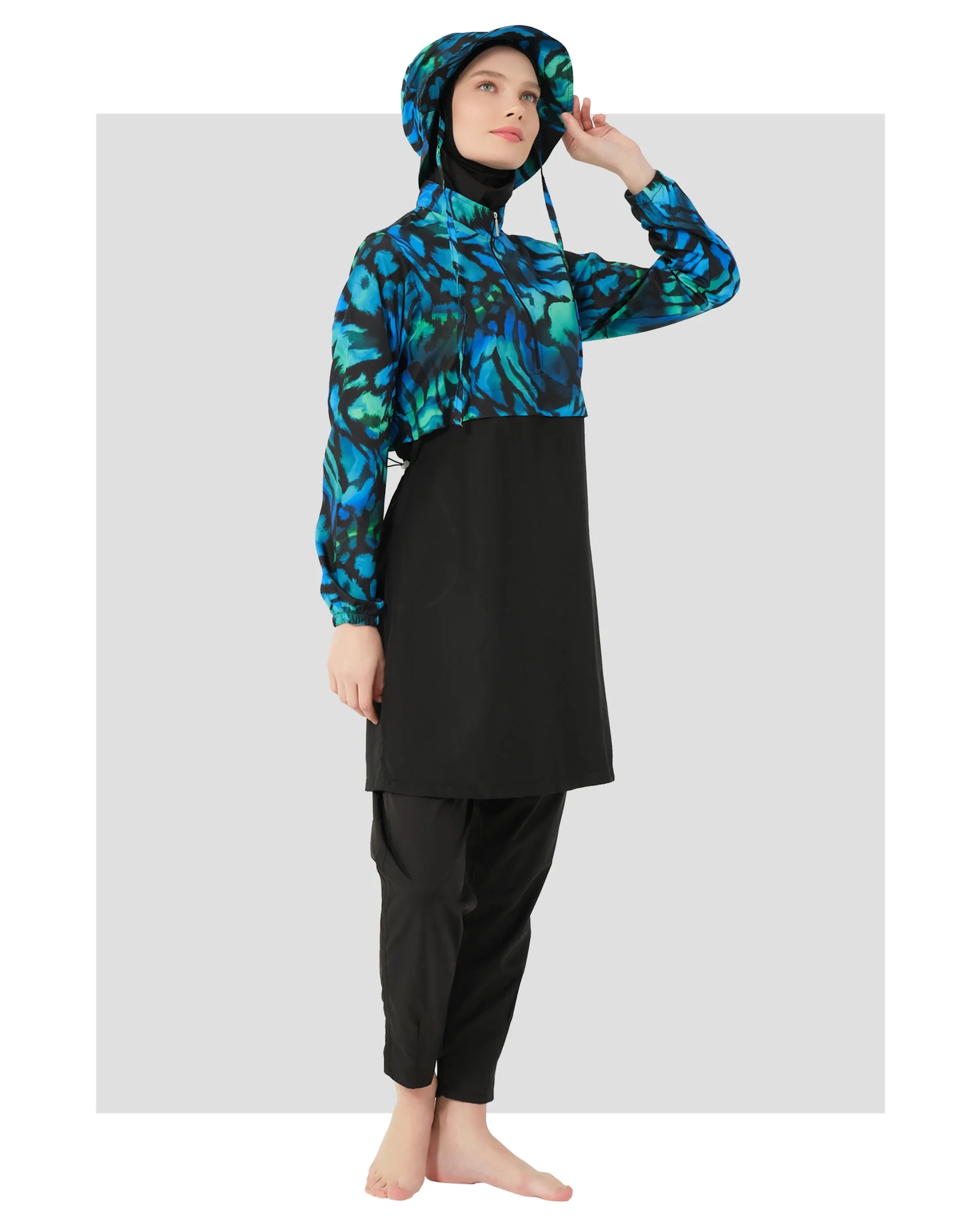 Woman in ocean-inspired print burkini set with black tunic and pants.