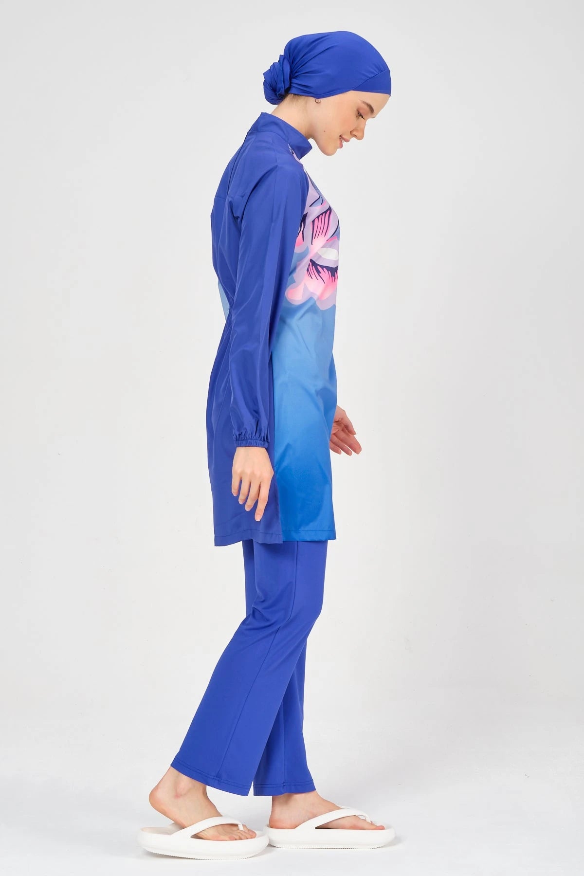 Model in blue modest swimsuit with abstract print, side profile.
