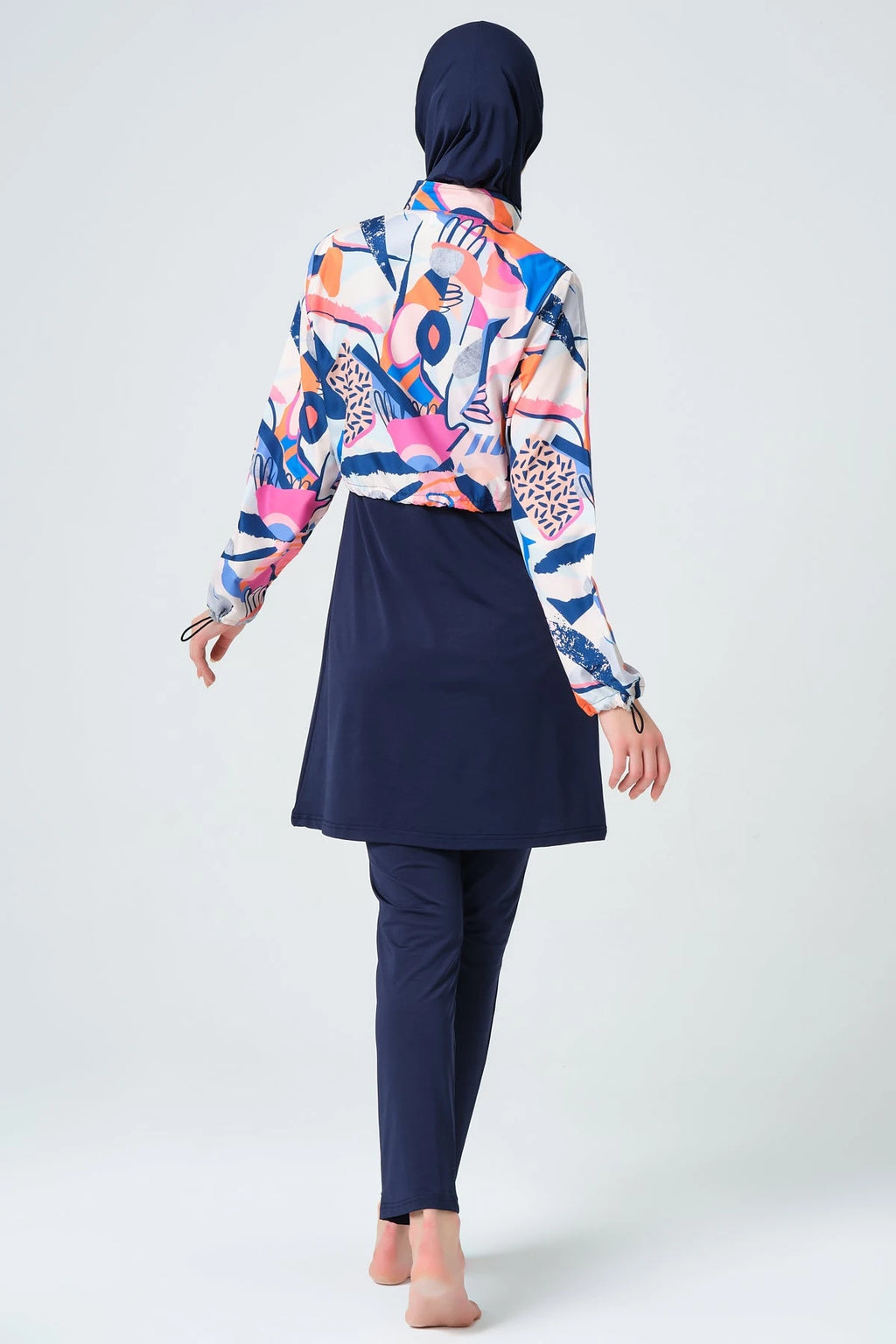 Woman in vibrant abstract print hijab swimwear set back view.