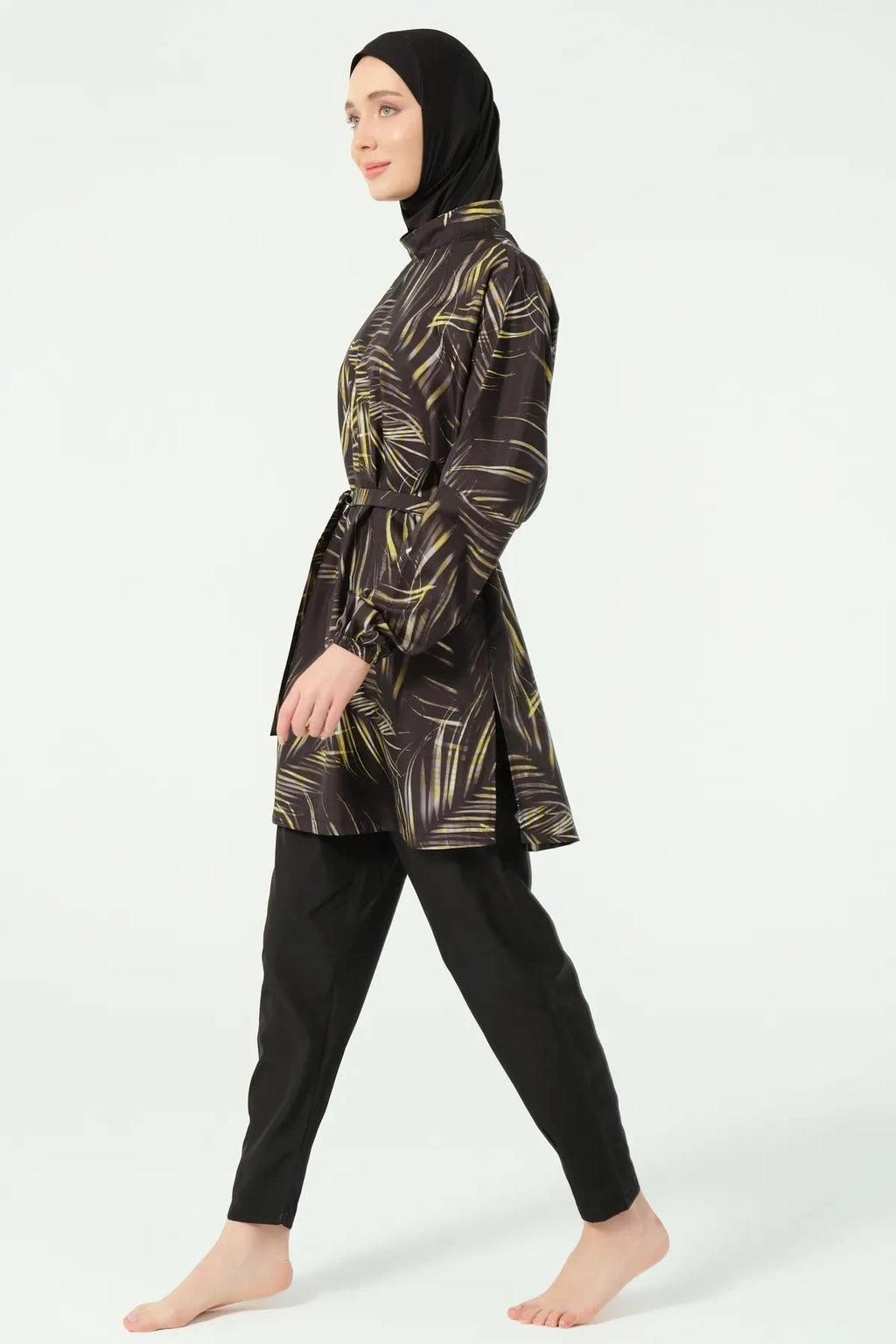 Model in black tropical print burkini, side profile showing movement.