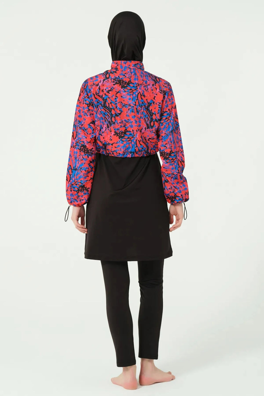 Woman in black hijab swimwear with abstract print jacket, back view.