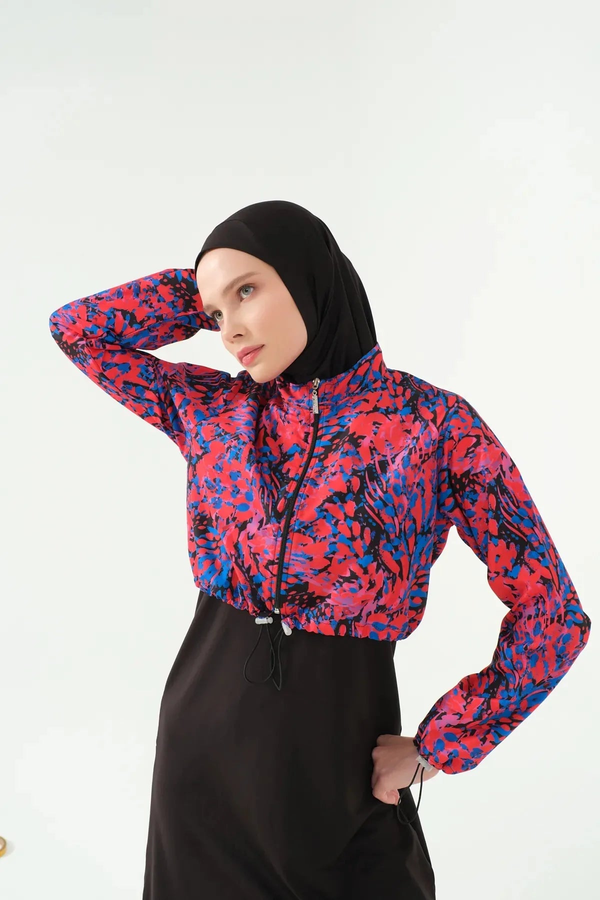 Close-up of woman in black hijab and abstract print swimwear jacket.