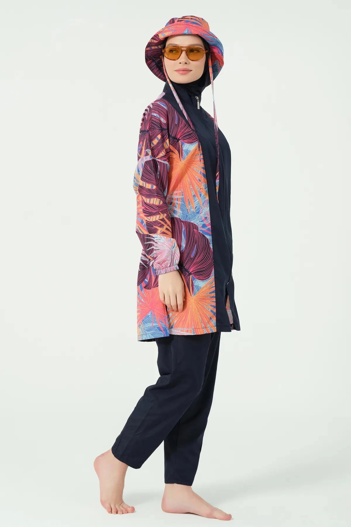 Woman in tropical print modest swimwear and bucket hat, profile view.