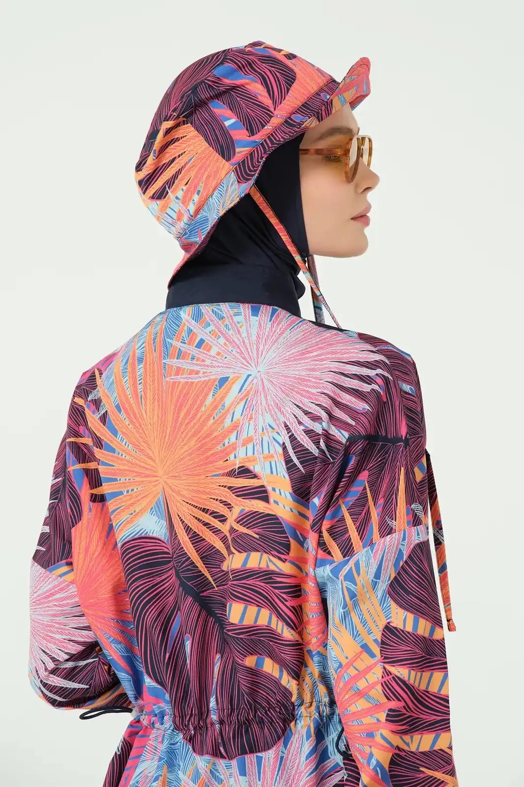 Woman in tropical print modest swimwear top and matching bucket hat, back detail.