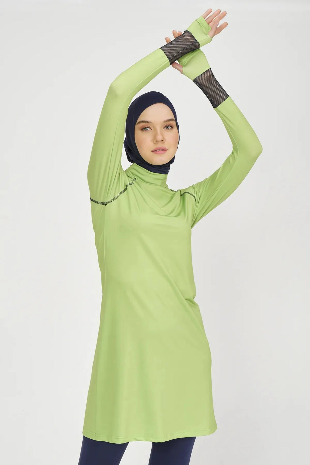 Model in lime green and navy hijab swimwear, upper body with arms raised.