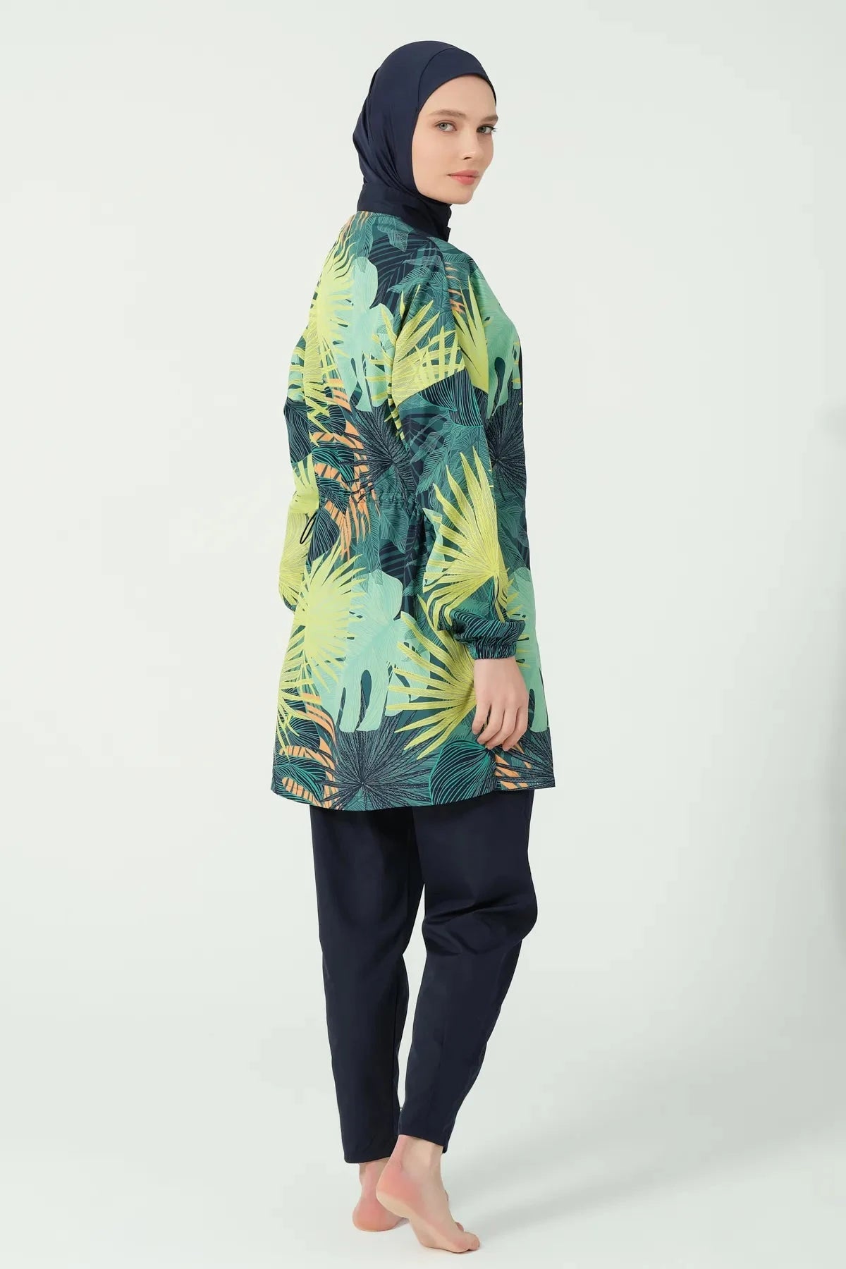 Model in tropical green burkini set with navy hijab, side profile.