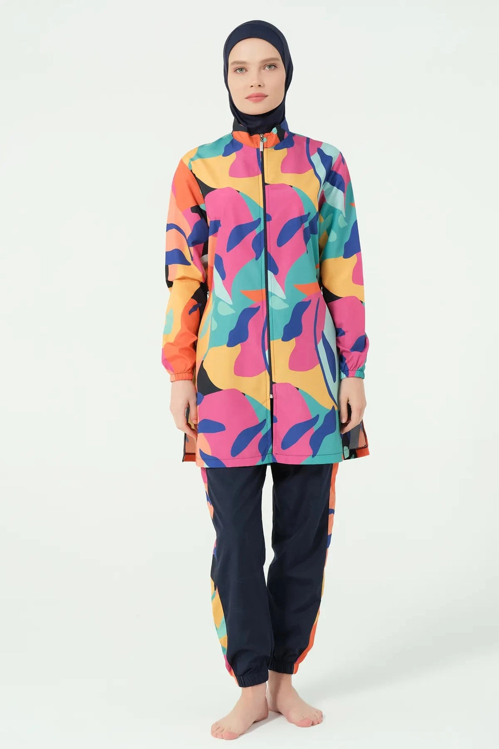 Woman in vibrant abstract print burkini set standing front view.