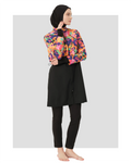 Woman in black hijab and vibrant watercolor print burkini top, side view.