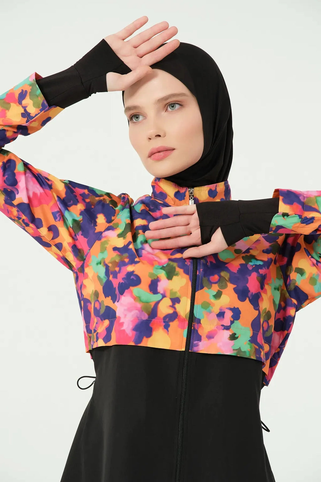 Woman in colorful burkini top showing thumb hole sleeves.