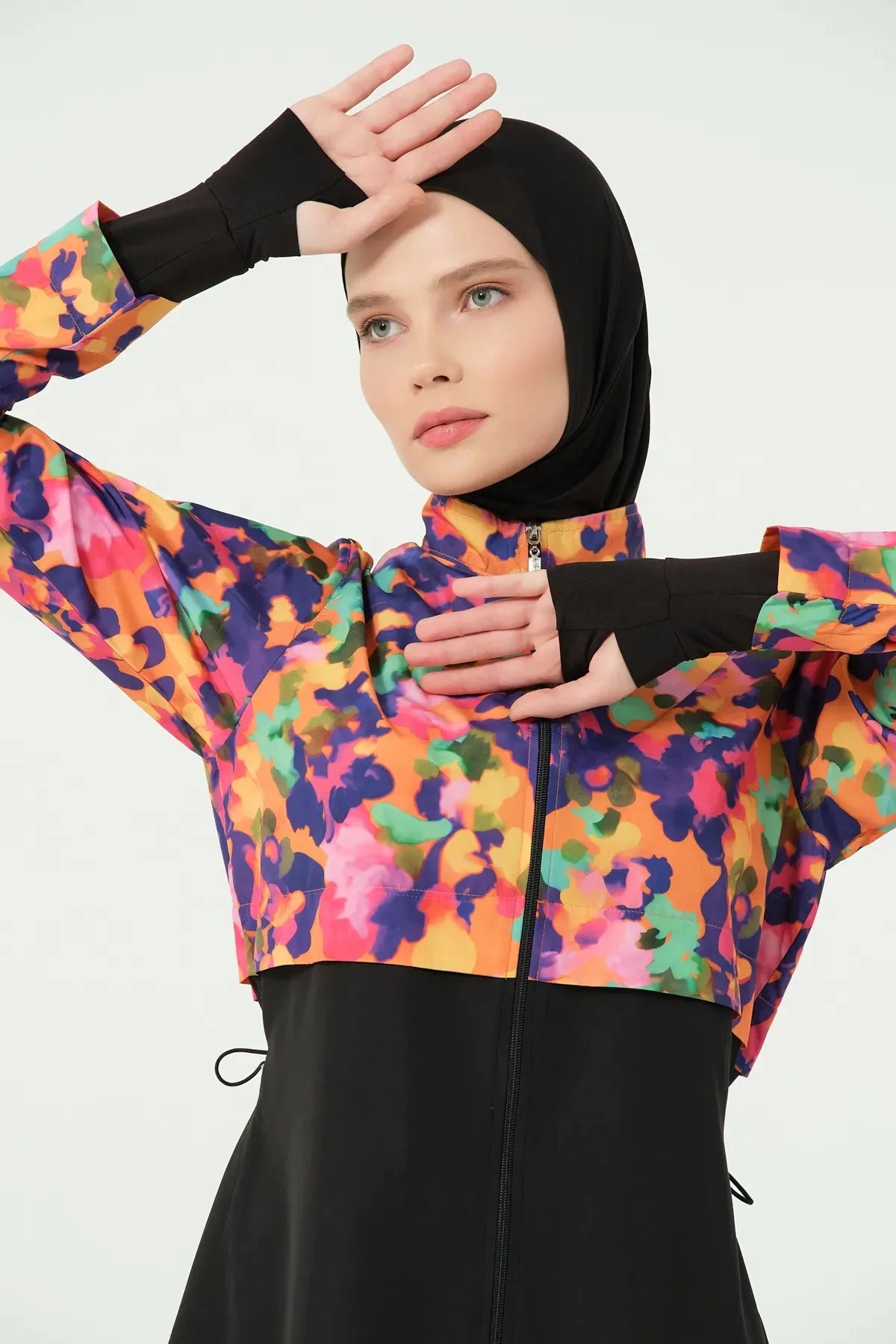 Woman in colorful burkini top showing thumb hole sleeves.