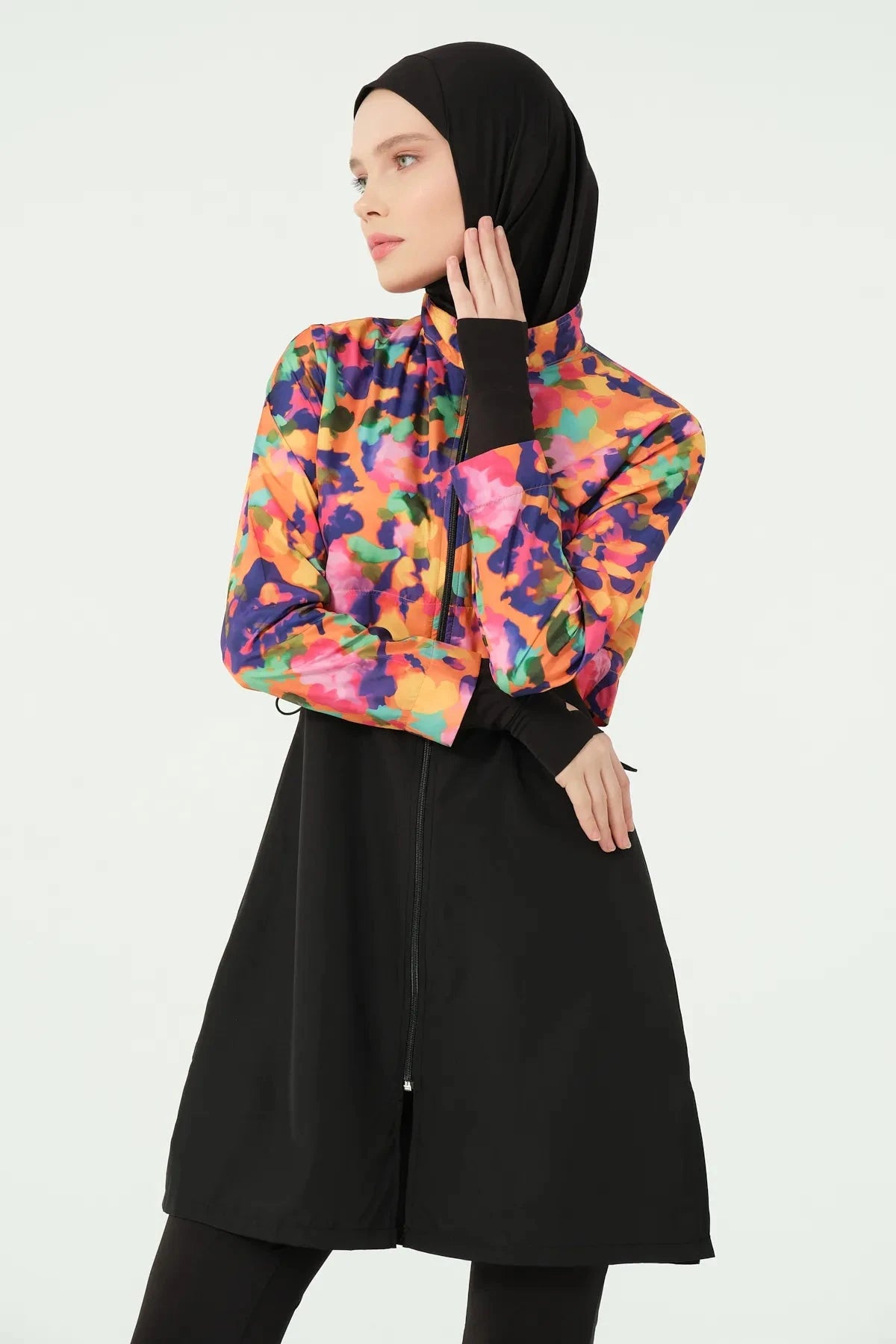 Woman in black hijab and colorful burkini set, front view.