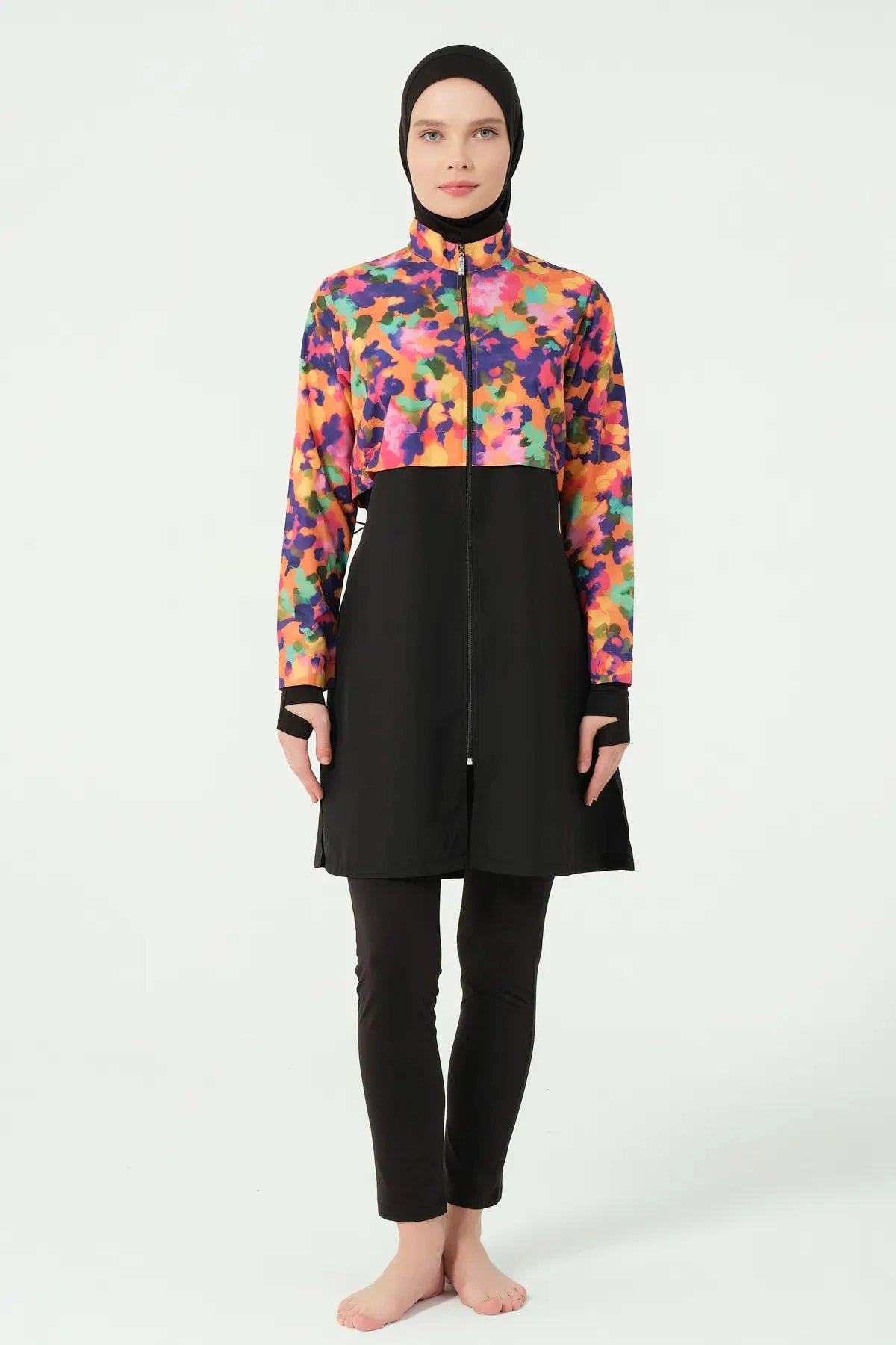 Woman in black hijab and vibrant watercolor print burkini, full front view.