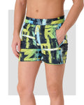Men's neon abstract print swim trunks, side view with hand in pocket.